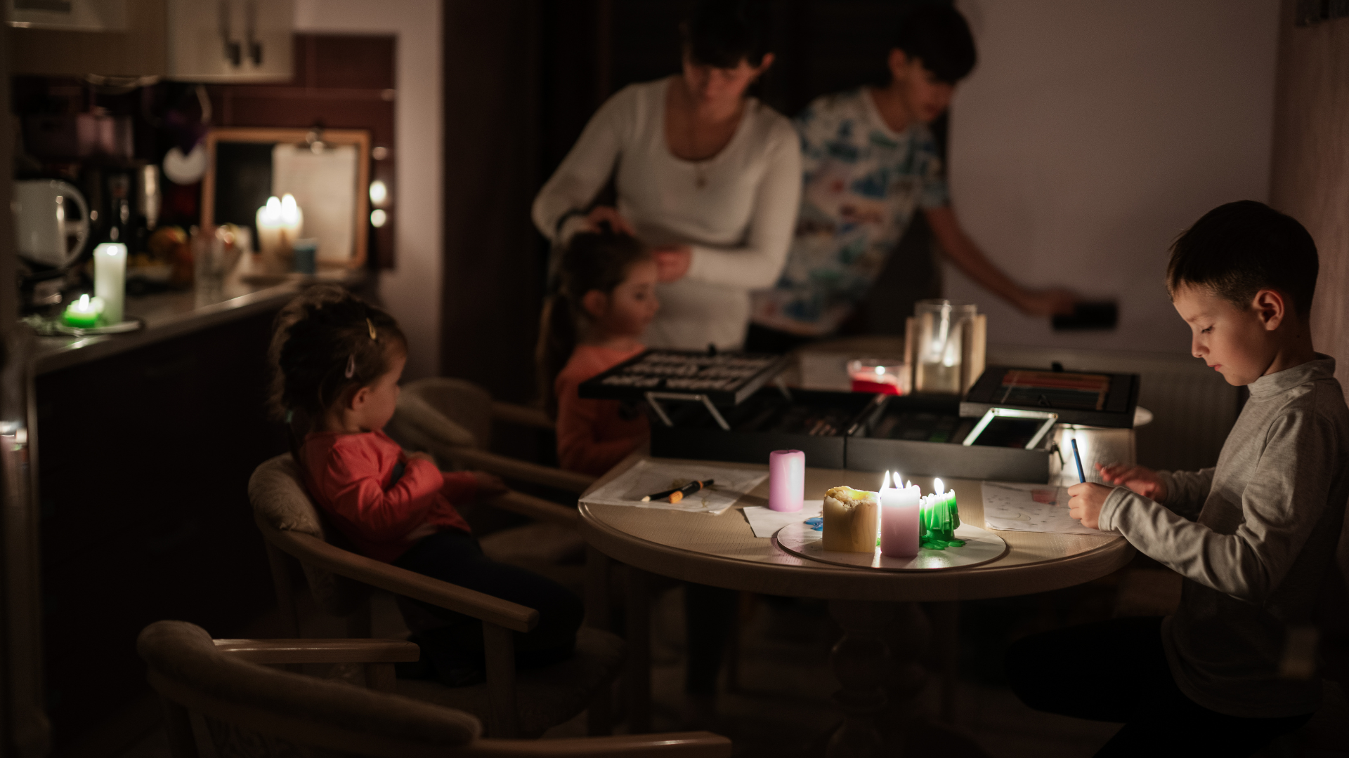 Famiglia riunita a tavola durante un blackout, illuminata solo da candele.
