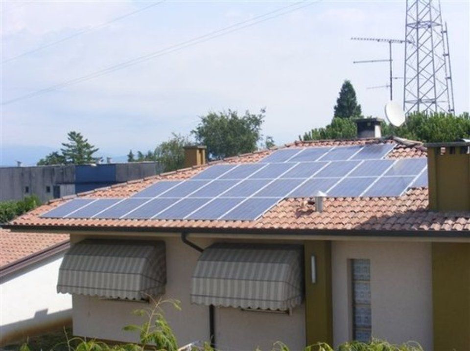 Pannelli solari installati su un tetto di tegole in terracotta, sotto un cielo sereno.