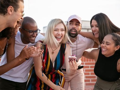 A group of people are standing around a woman holding a cell phone.
