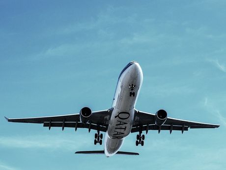 A qatar airplane is flying through a clear blue sky