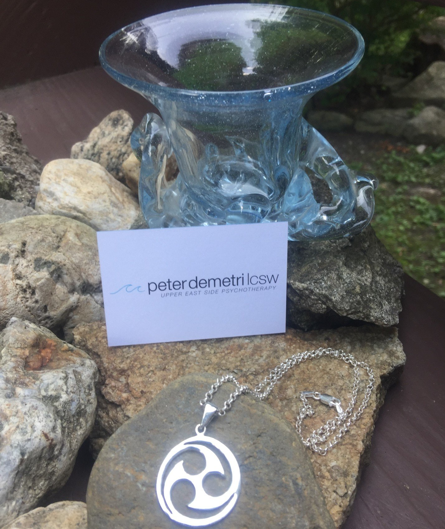 A necklace is sitting on a rock next to a business card