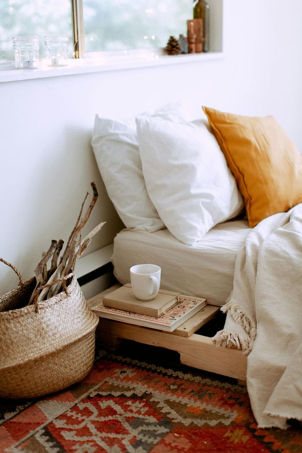 A bed with white sheets and pillows in a bedroom next to a window.