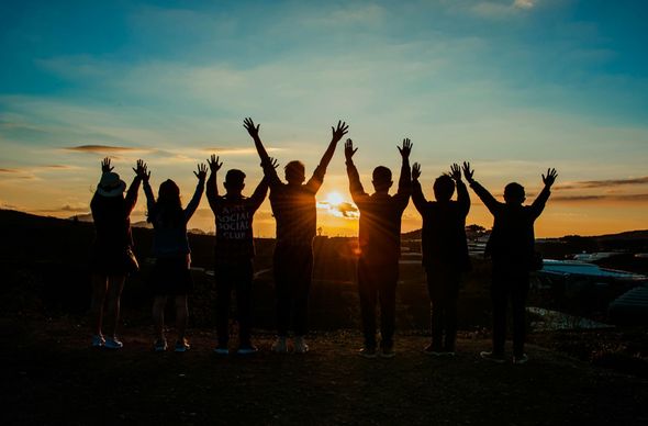 A group of people are standing next to each other with their hands in the air.