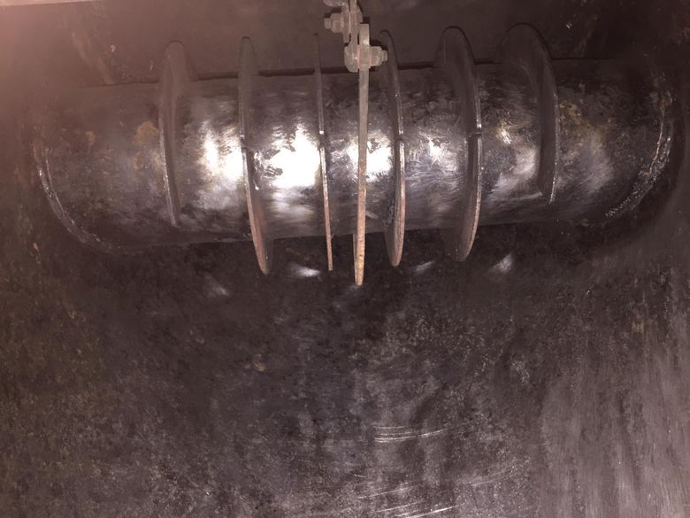 Interno di un apparecchio di metallo scuro con una vite rotante e aste metalliche pendenti.