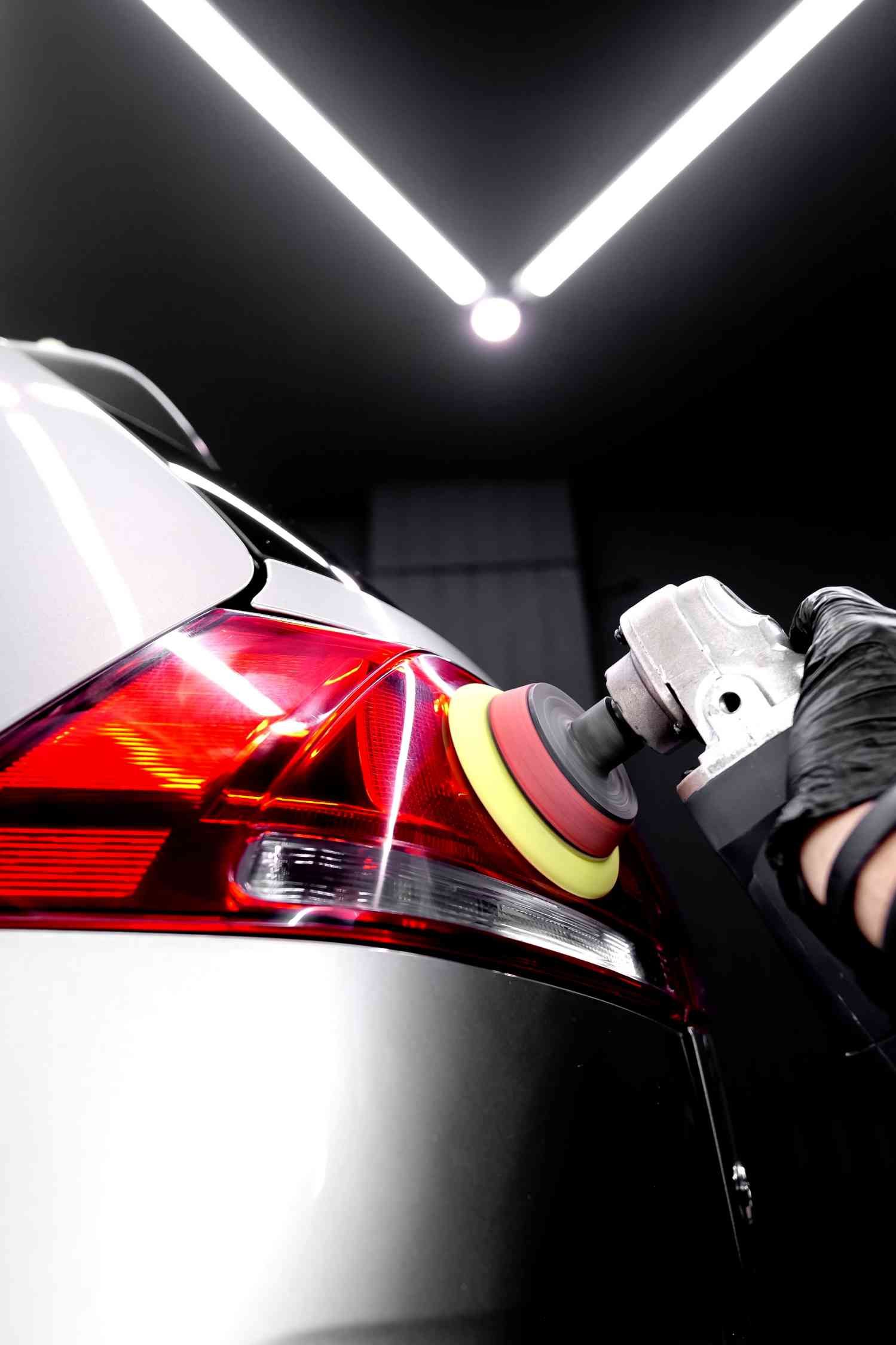 a person is polishing the tail light of a car - after paint correction process