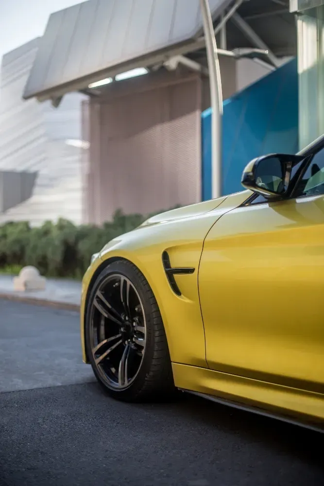 applying of Ceramic Coating for paint protection, a bright yellow BMW M4 is now parked in front of a building.