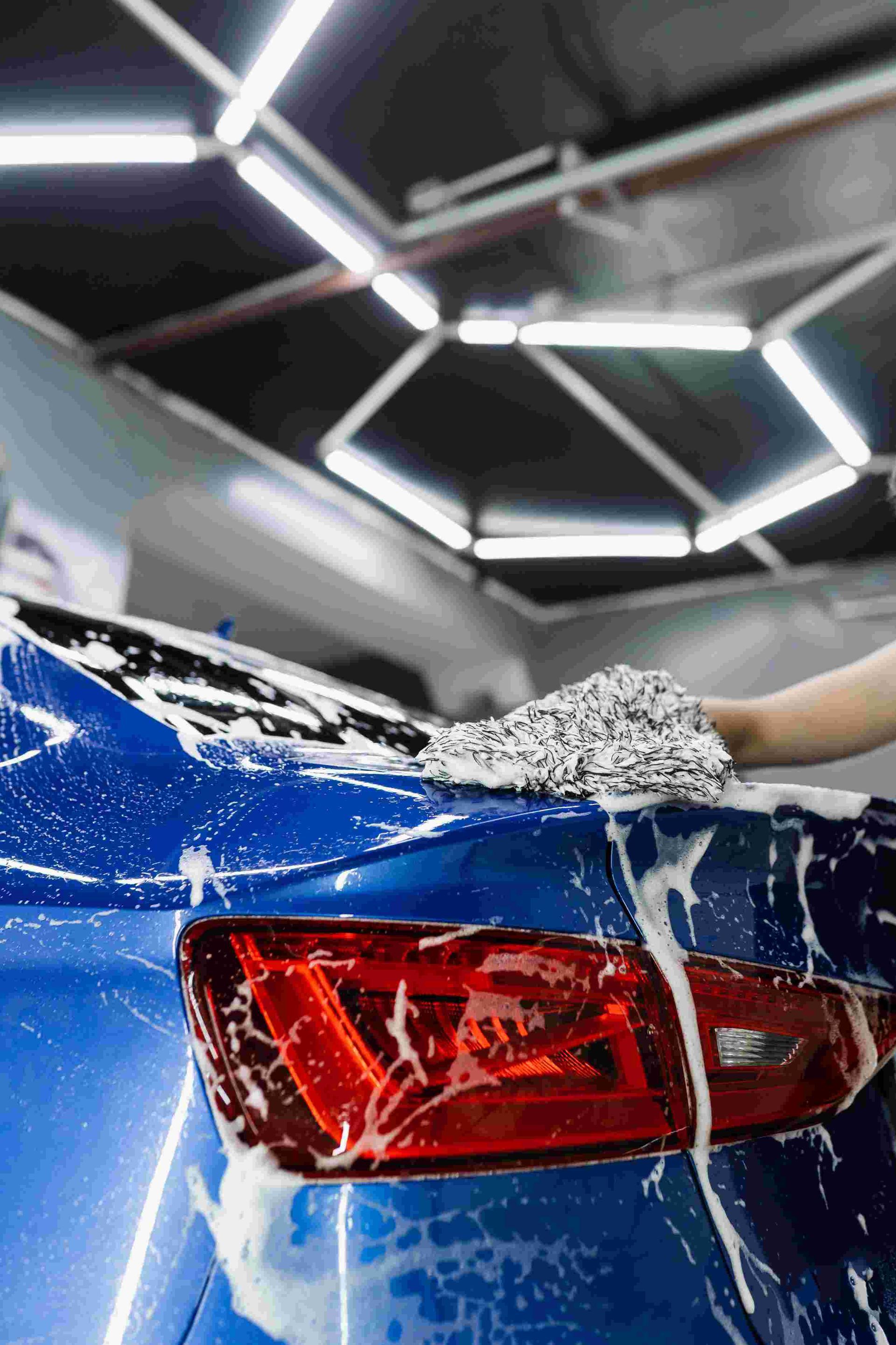 a person is washing a blue car in a garage - car detailing experts in Rouse Hill