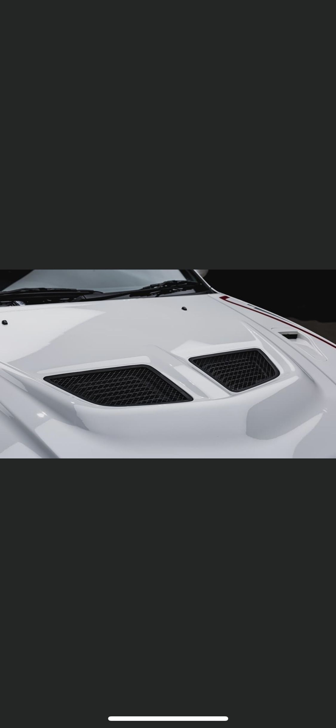 A close up of a white car hood with black vents also got an application of Ceramic Coating.