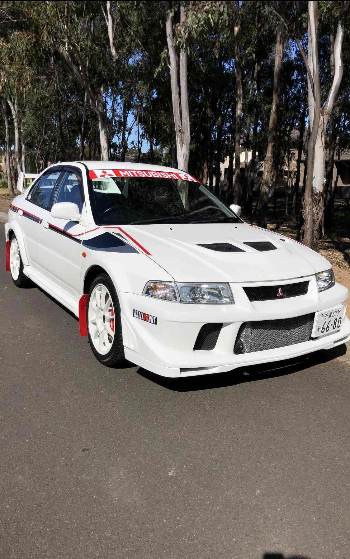 a white mitsubishi car is parked on the side of the road with ceramic coating applied to bring the shine