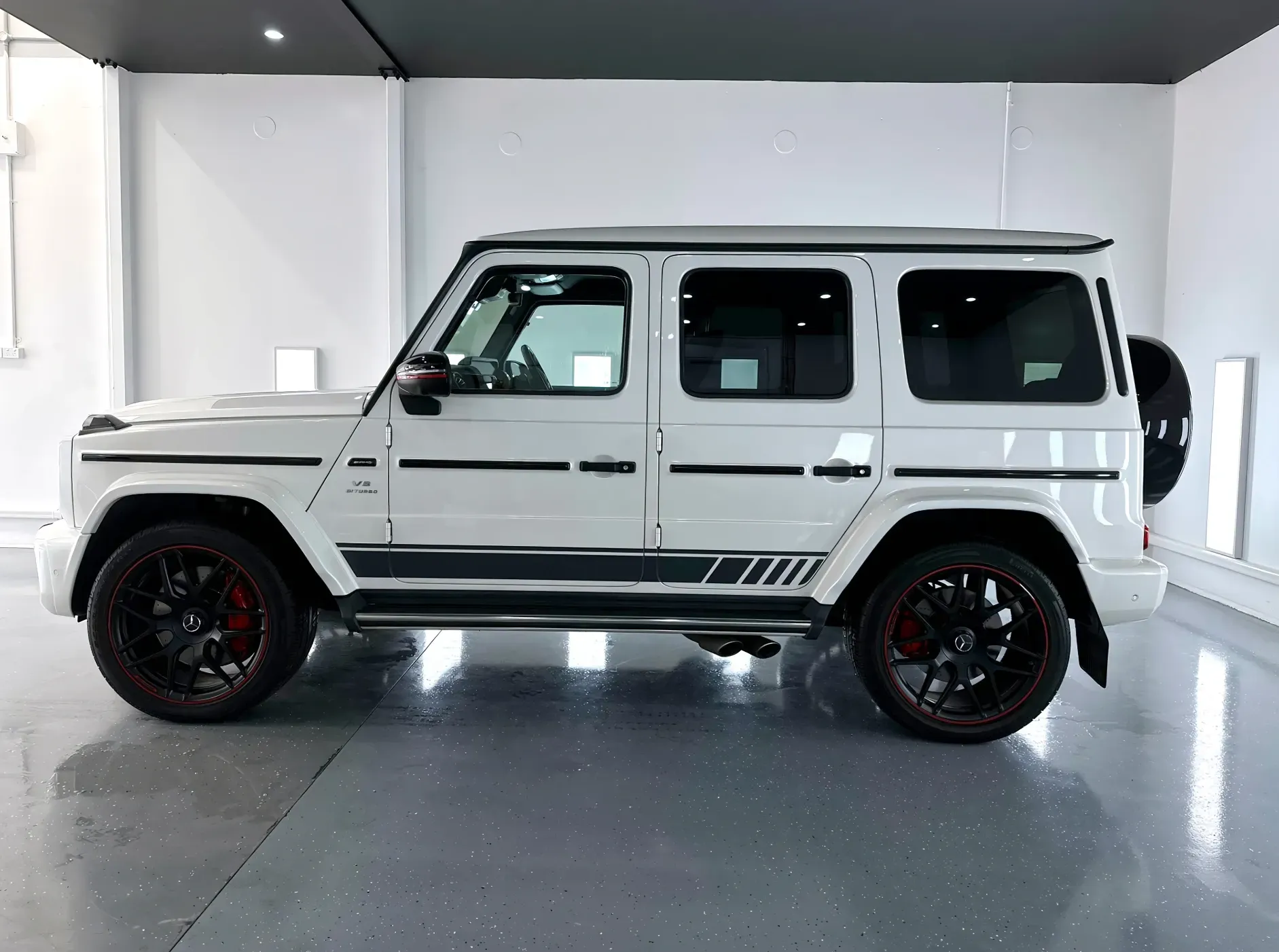A white mercedes benz g63 amg is parked in a garage after being Ceramic Coated for paint protection.