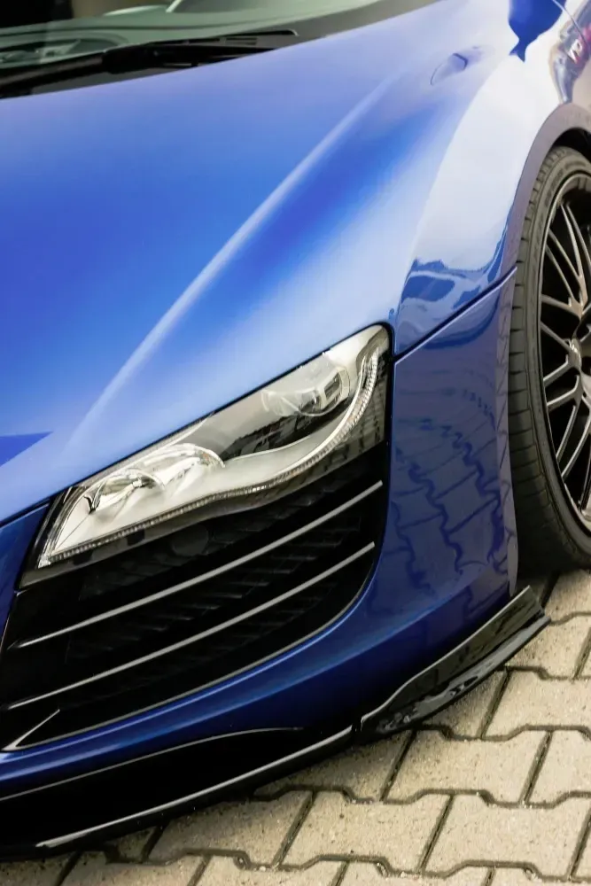 A blue sports car is parked on a brick pavement, after ceramic coating applied.