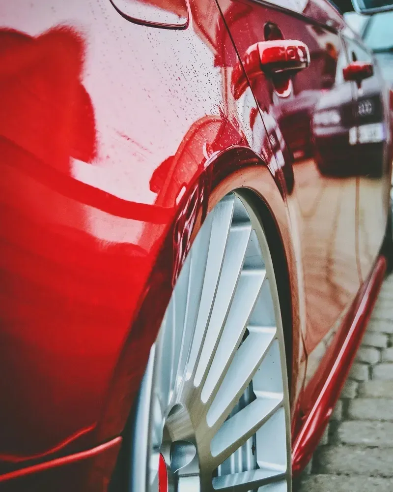 A red car is parked on a cobblestone street