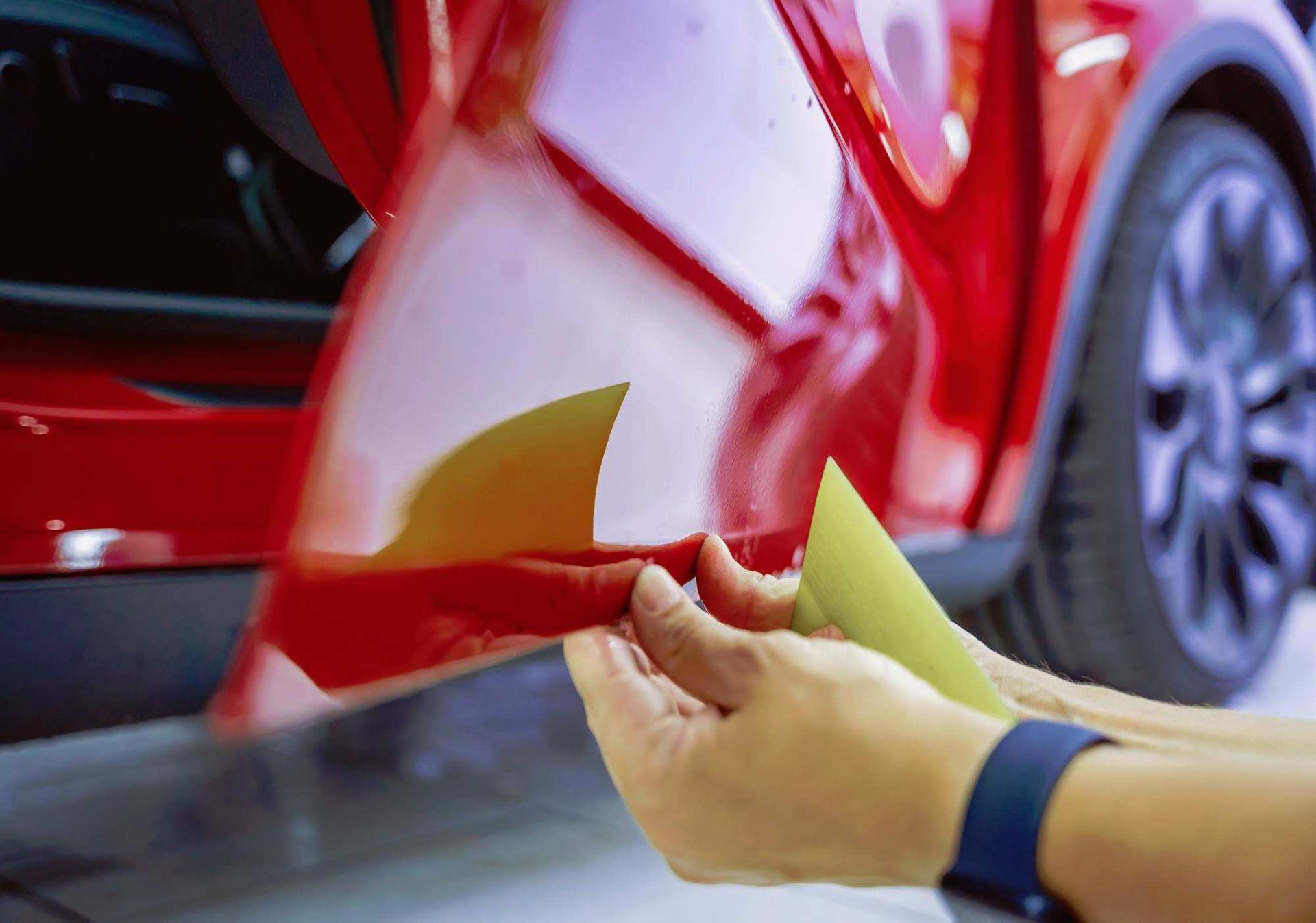 a person is holding a piece of yellow paper in front of a red car