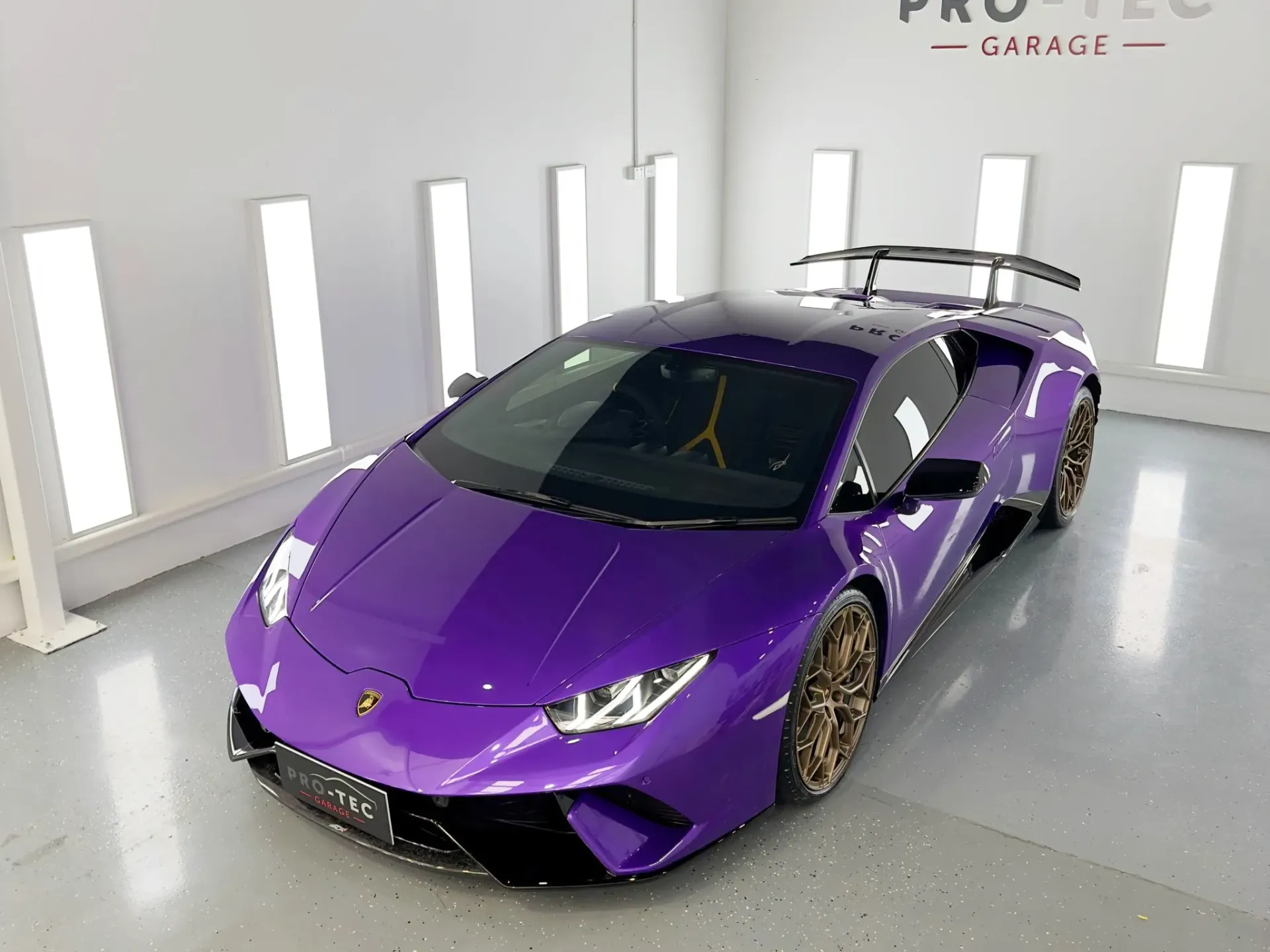A purple lamborghini huracan is parked in a garage.