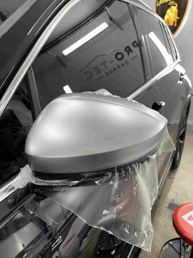 a person wearing a glove is working on applying a paint protection film (ppf)