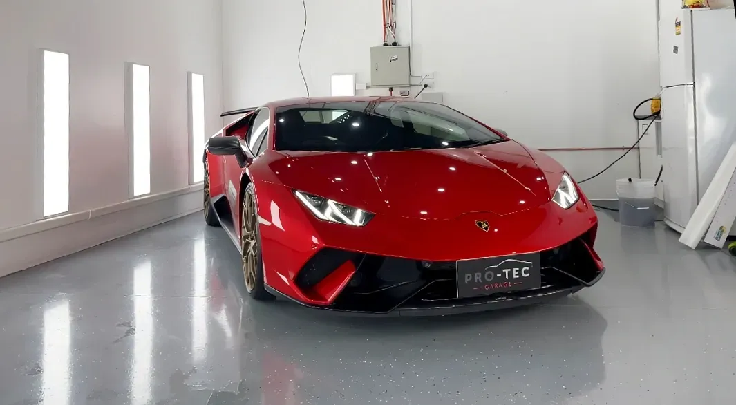 A red lamborghini huracan is parked in a garage getting a ppf completed and paint correction.
