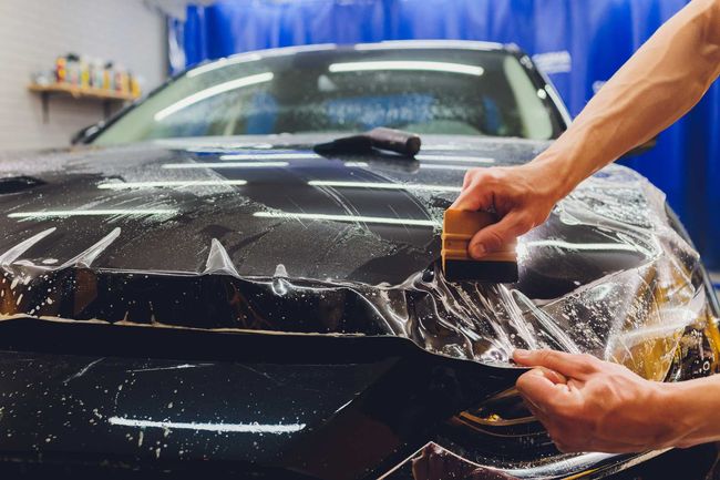 a person is applying a protective film to the bonnet of a car