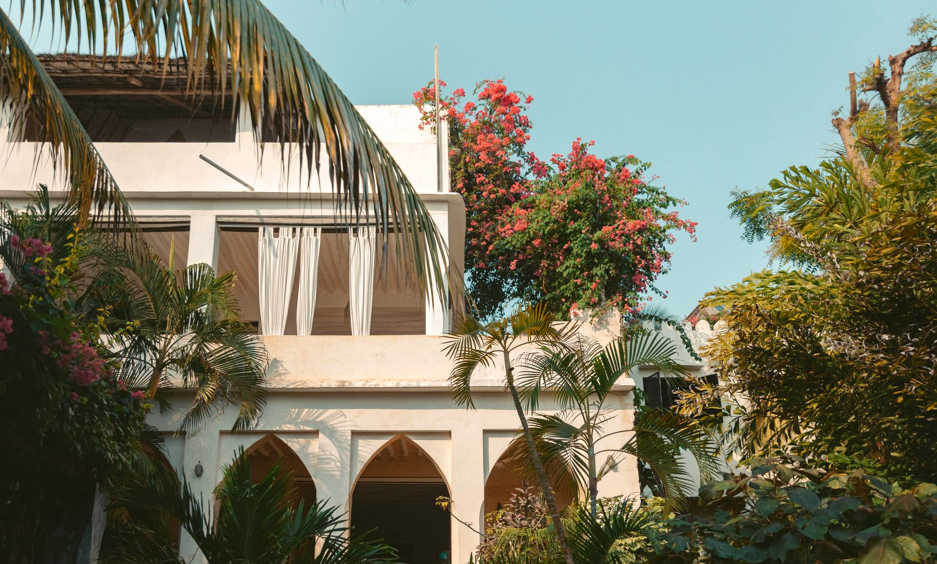 Traditional Swahili-style architecture of Banana House with balconies and lush tropical plants during day view