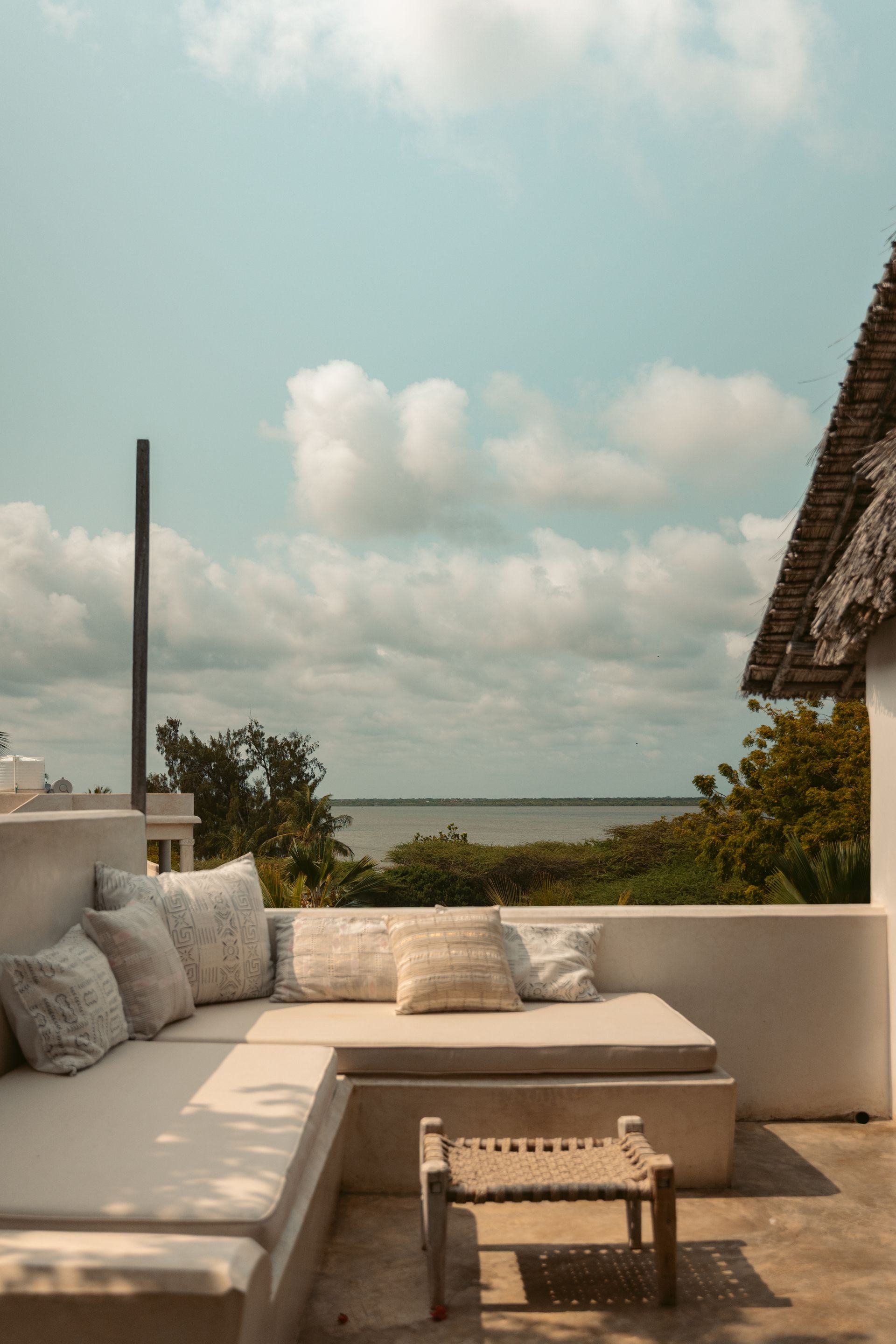 View of the blue tropical sky and clouds above a traditional thatched rooftop