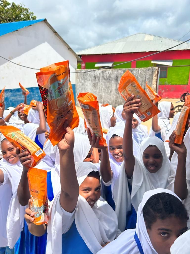 Students holding reusable pad packages during awareness event