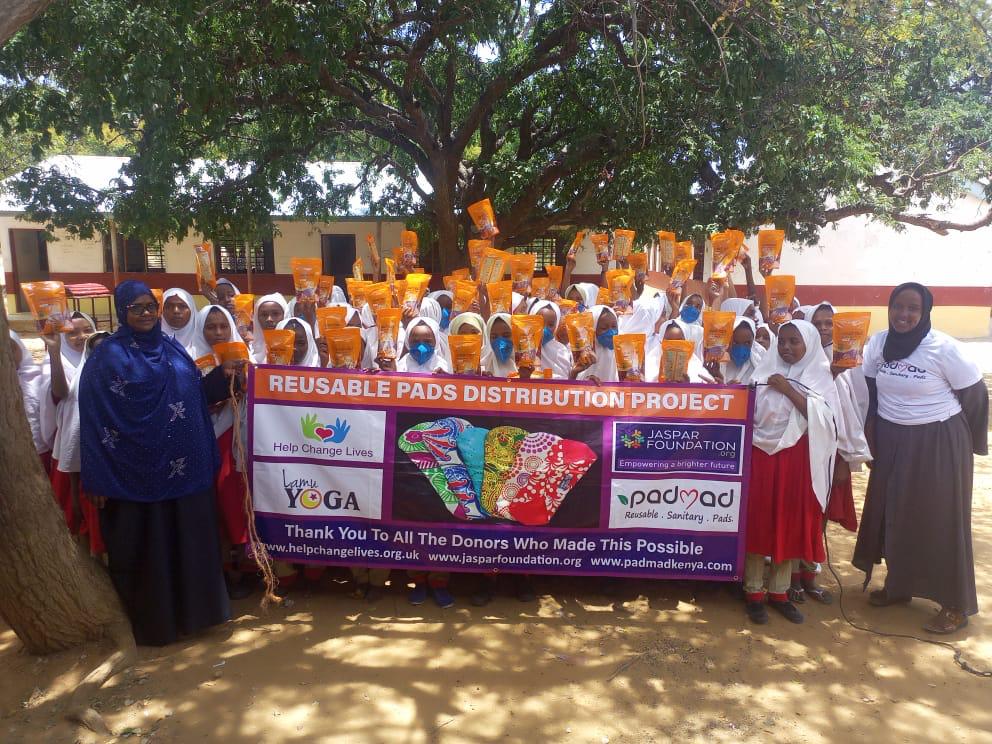 Students holding reusable pad packages during awareness event