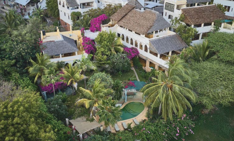 Scenic aerial view of Banana House & Wellness Centre with tropical gardens, palm trees, and traditional Swahili architecture in Lamu.
