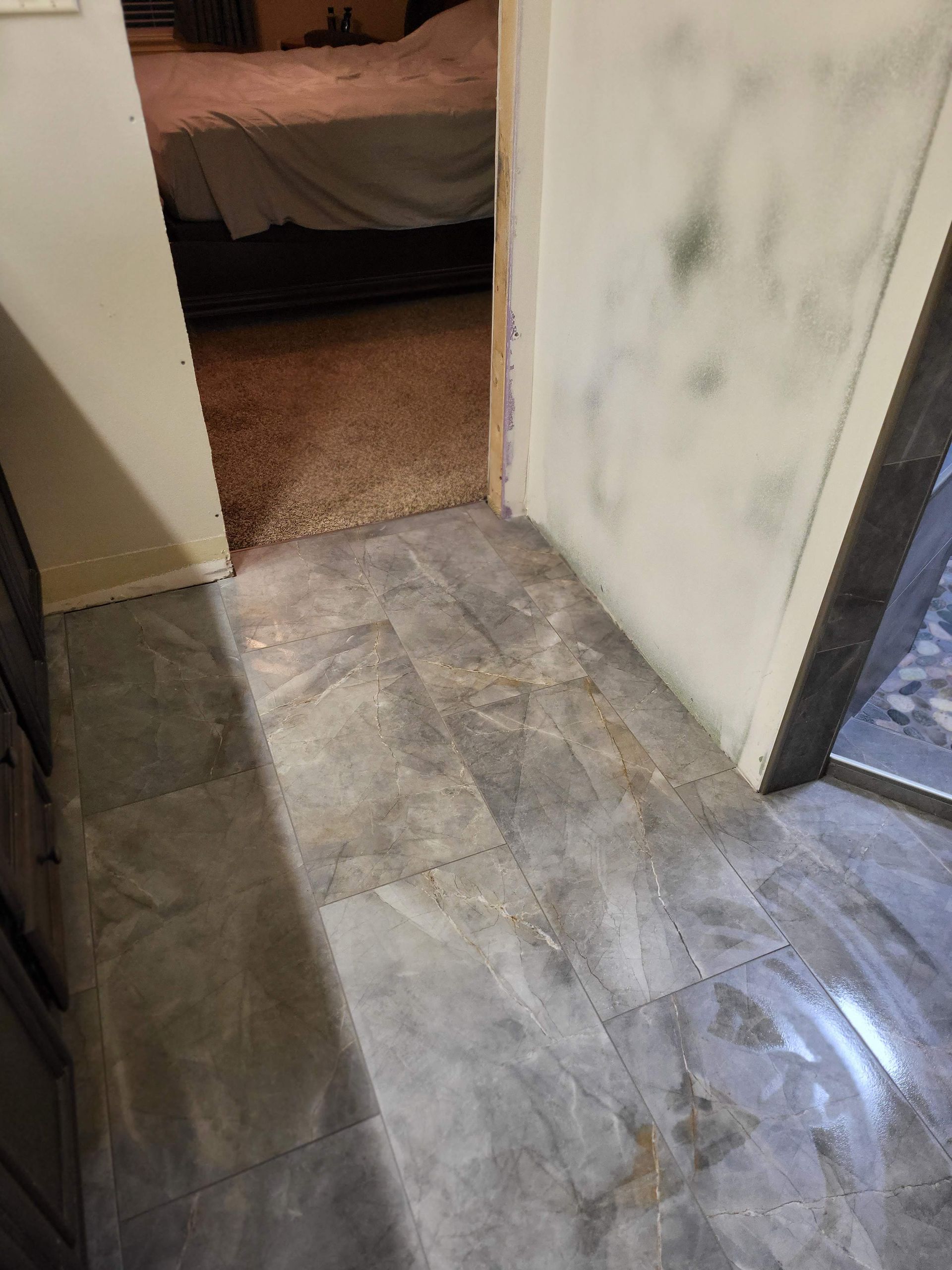 Gray tile floor at a doorway, leading into a room with carpeted flooring.