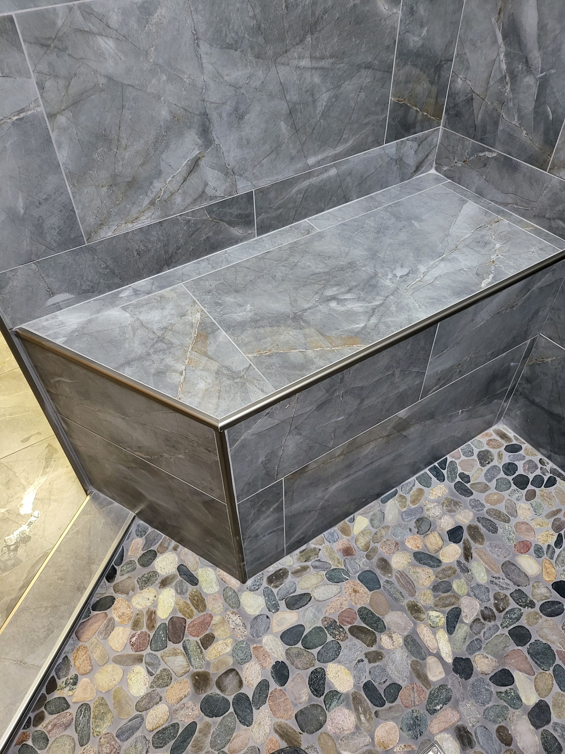 Stone bathtub or basin in a tiled bathroom corner with a mosaic floor.