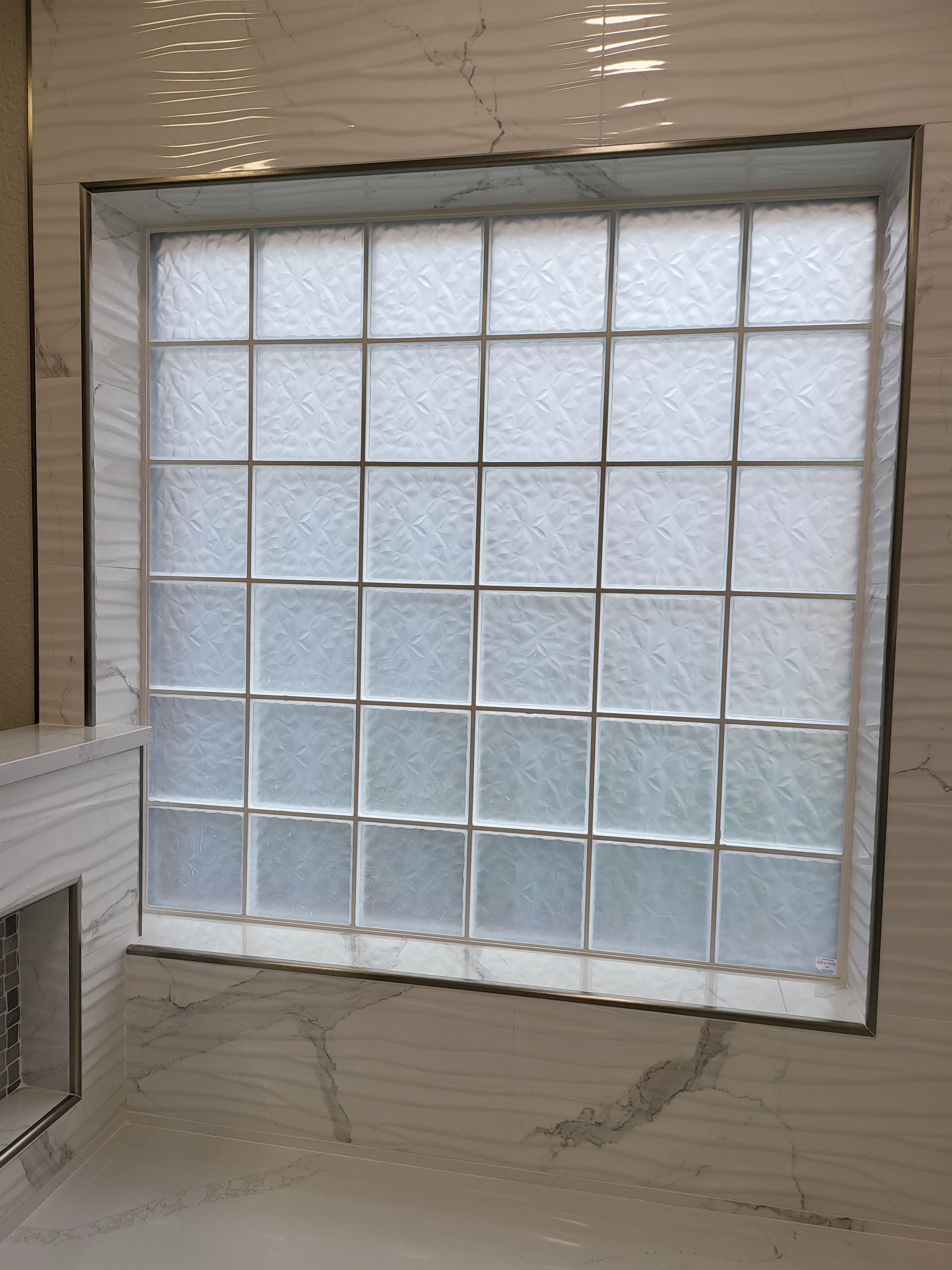 Frosted glass block window in a beige wall, with a white sink edge visible at left.