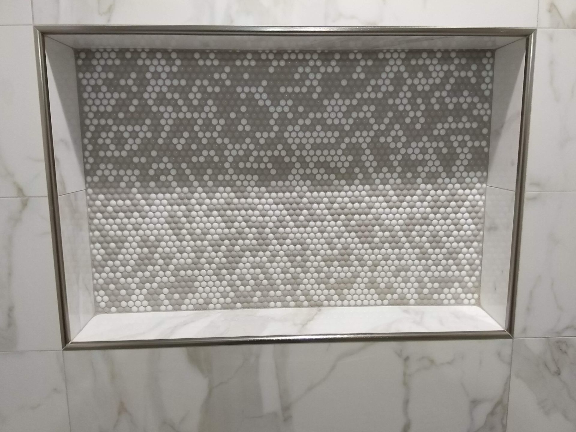 Rectangular bathroom mirror with patterned glass and a white marble tile surround