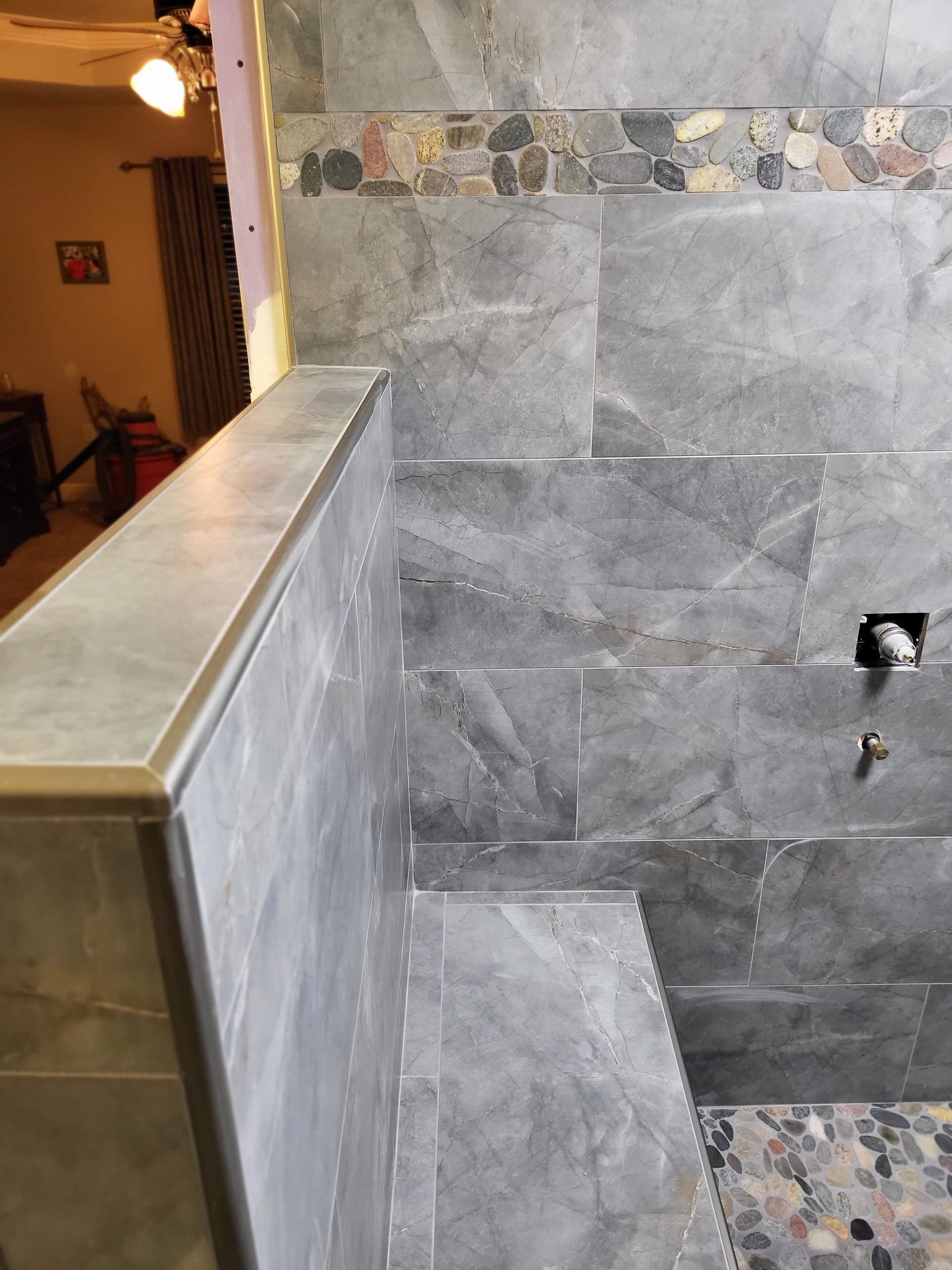 Gray tiled wall and ledge beside a staircase or landing in an indoor hallway