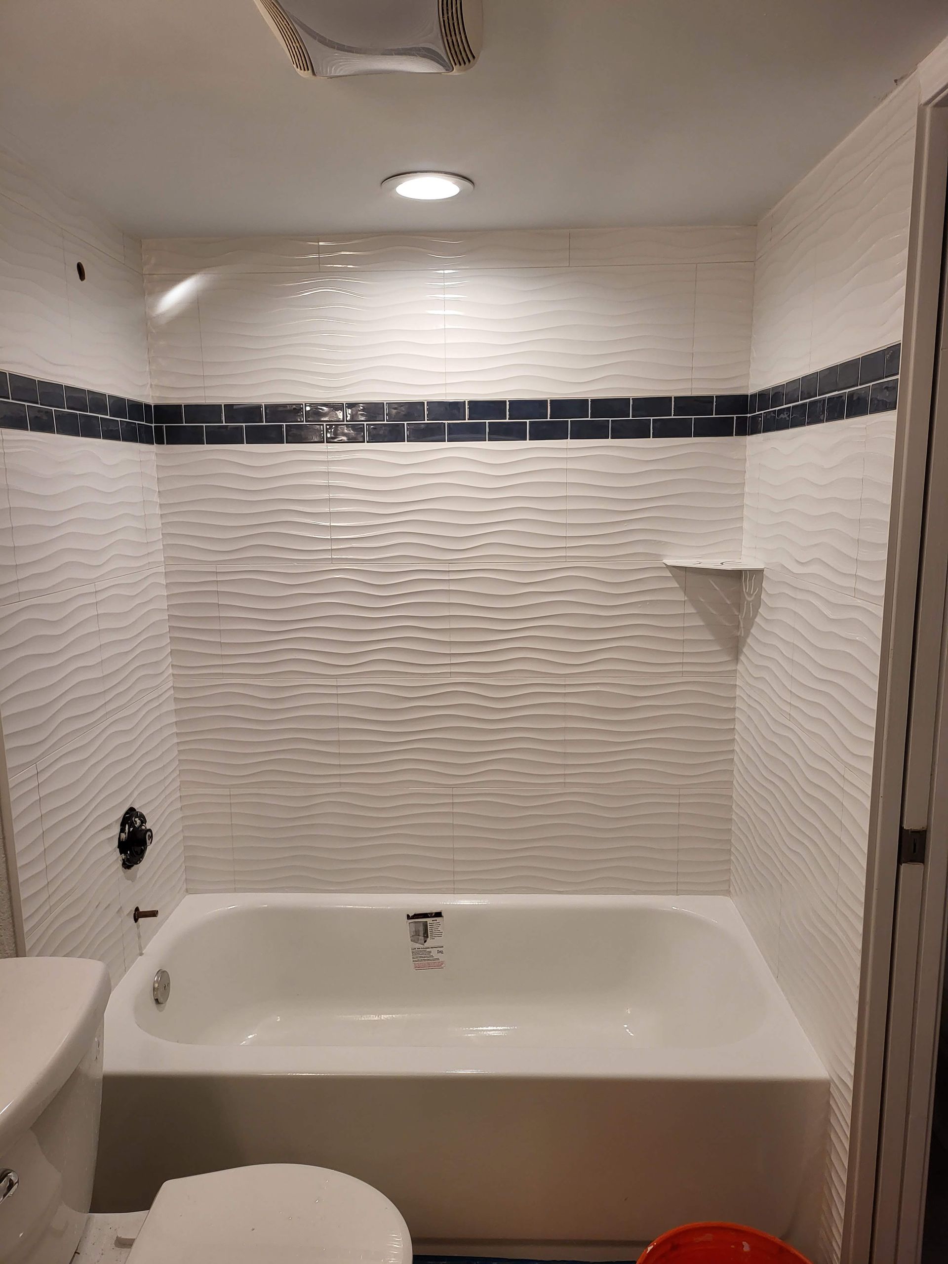 Empty bathroom with a white bathtub, tiled walls, and a dark decorative border.