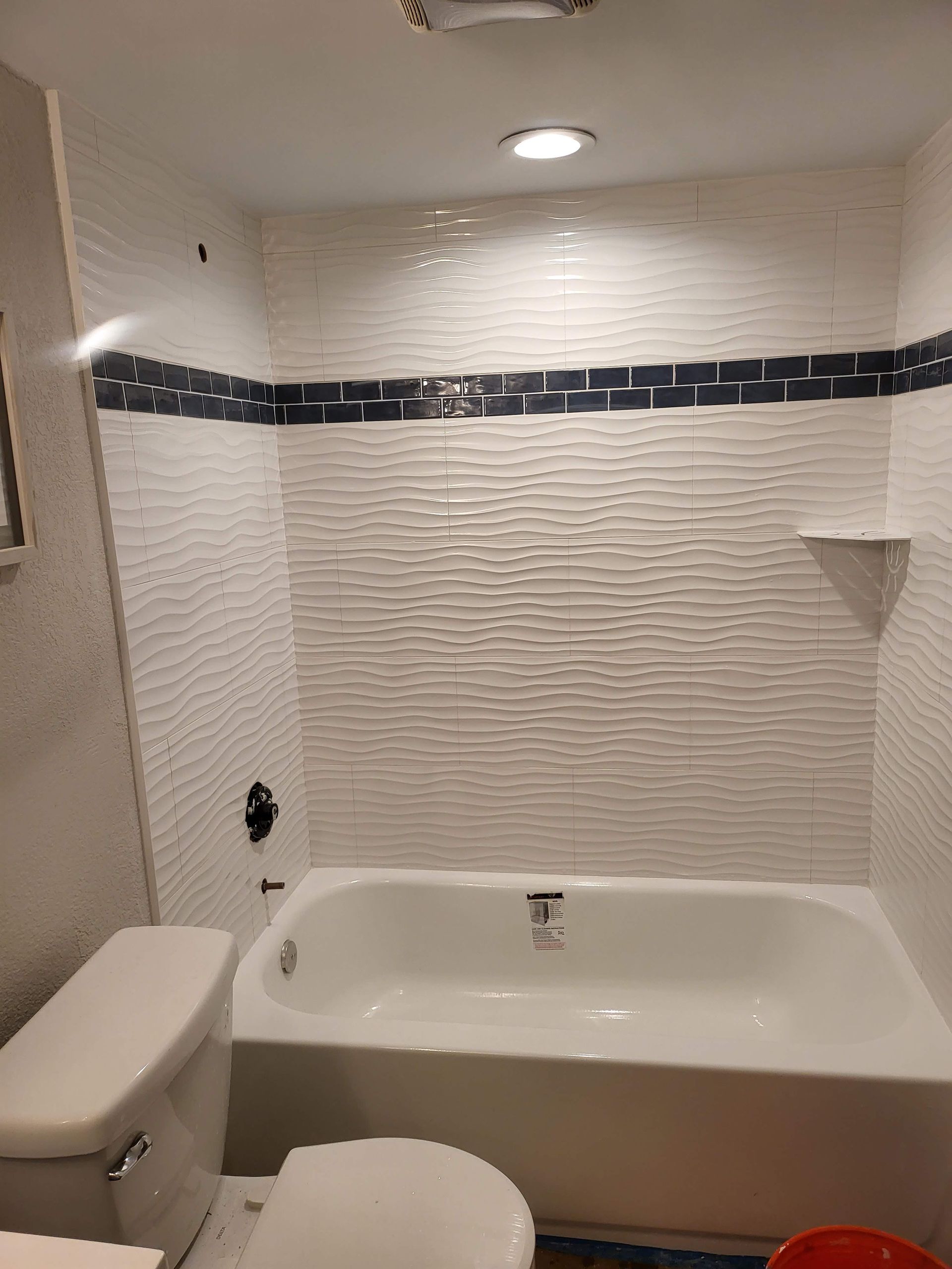 Small bathroom with a white bathtub, tiled walls, toilet, and recessed ceiling light.