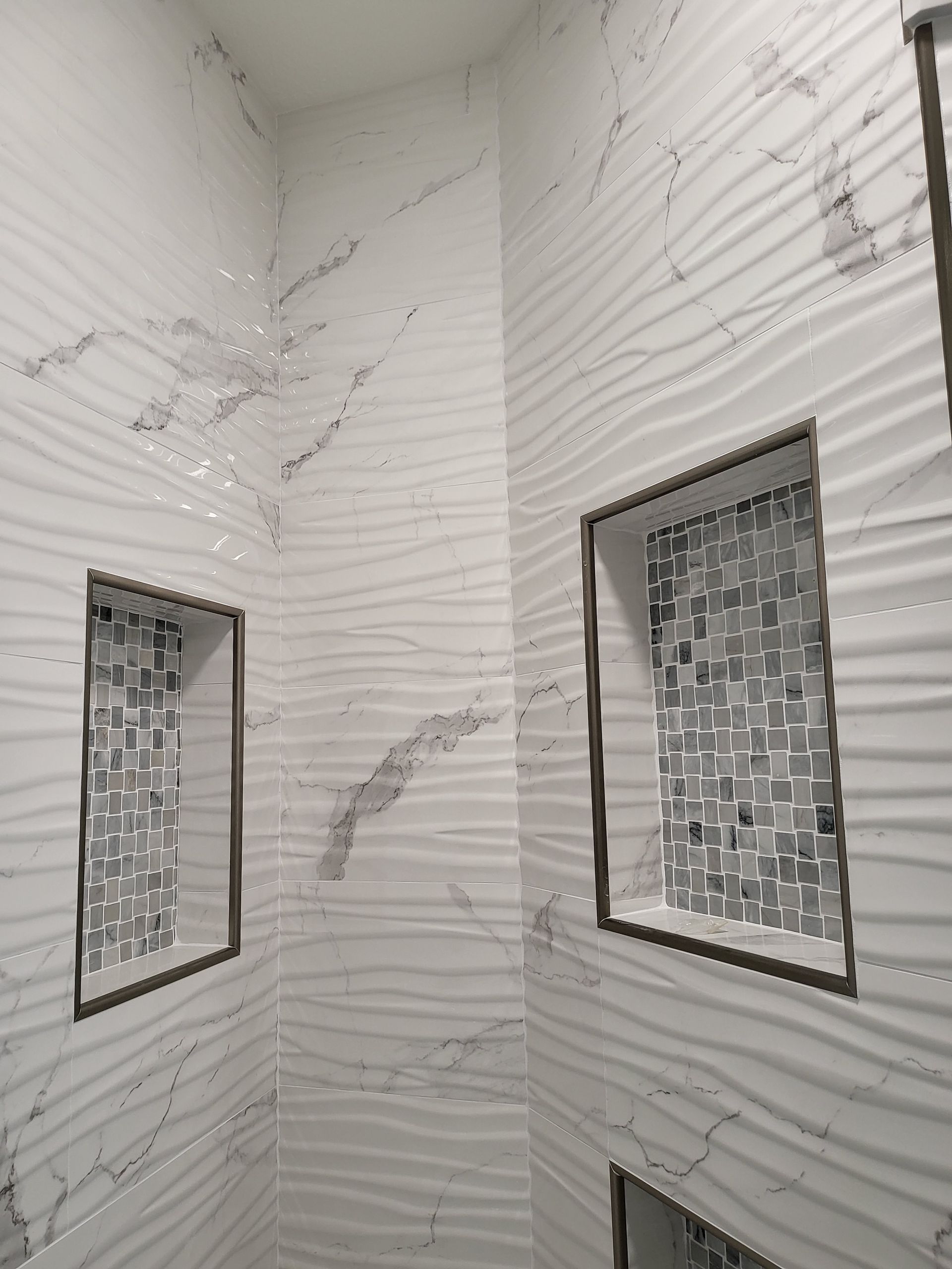 Corner of a tiled bathroom/shower with two frosted windows and water stains on the walls.