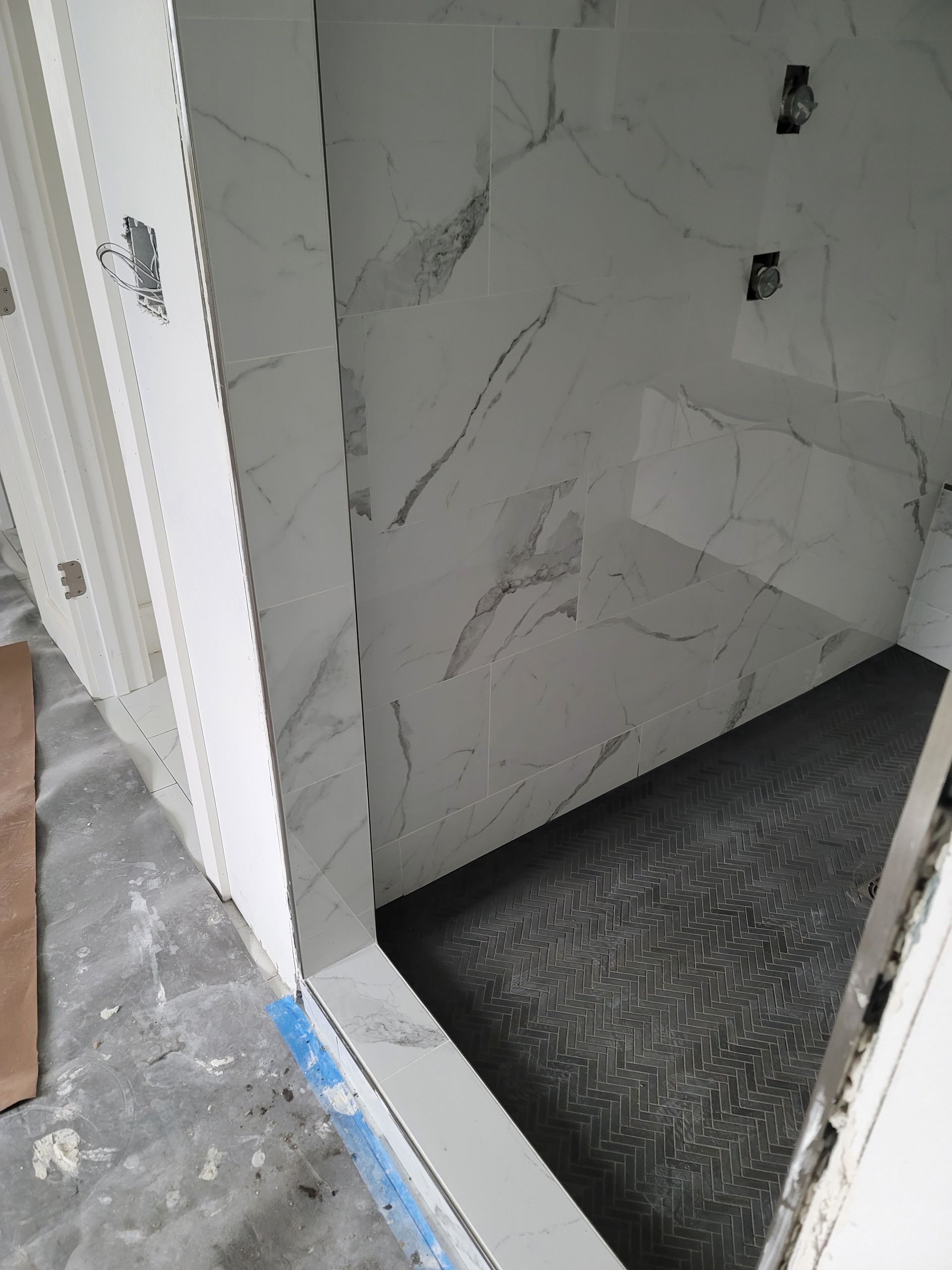Partially tiled doorway opening into a room with a dark floor and white walls