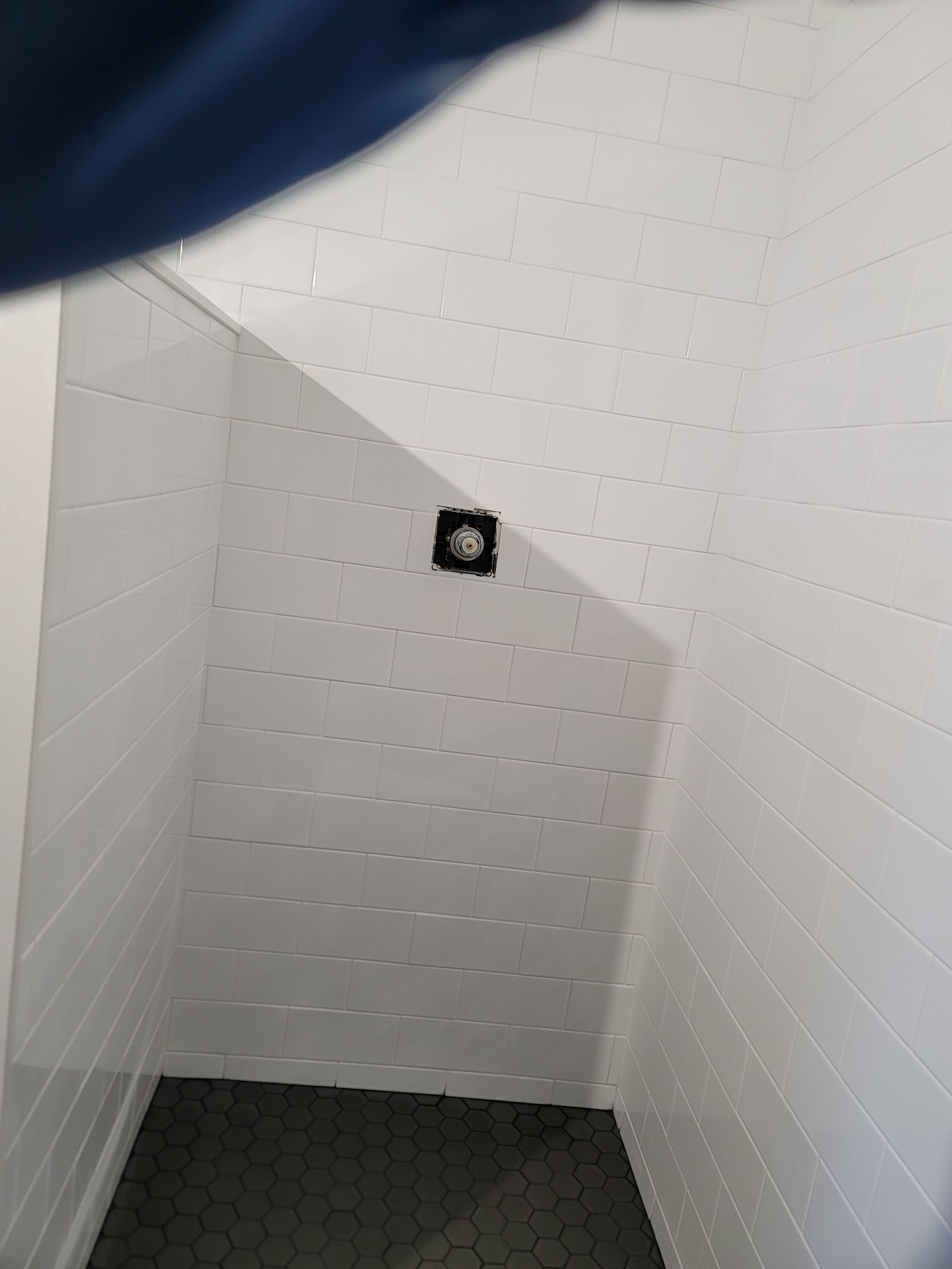Empty white stairwell with dark carpeted steps and a small black wall fixture.