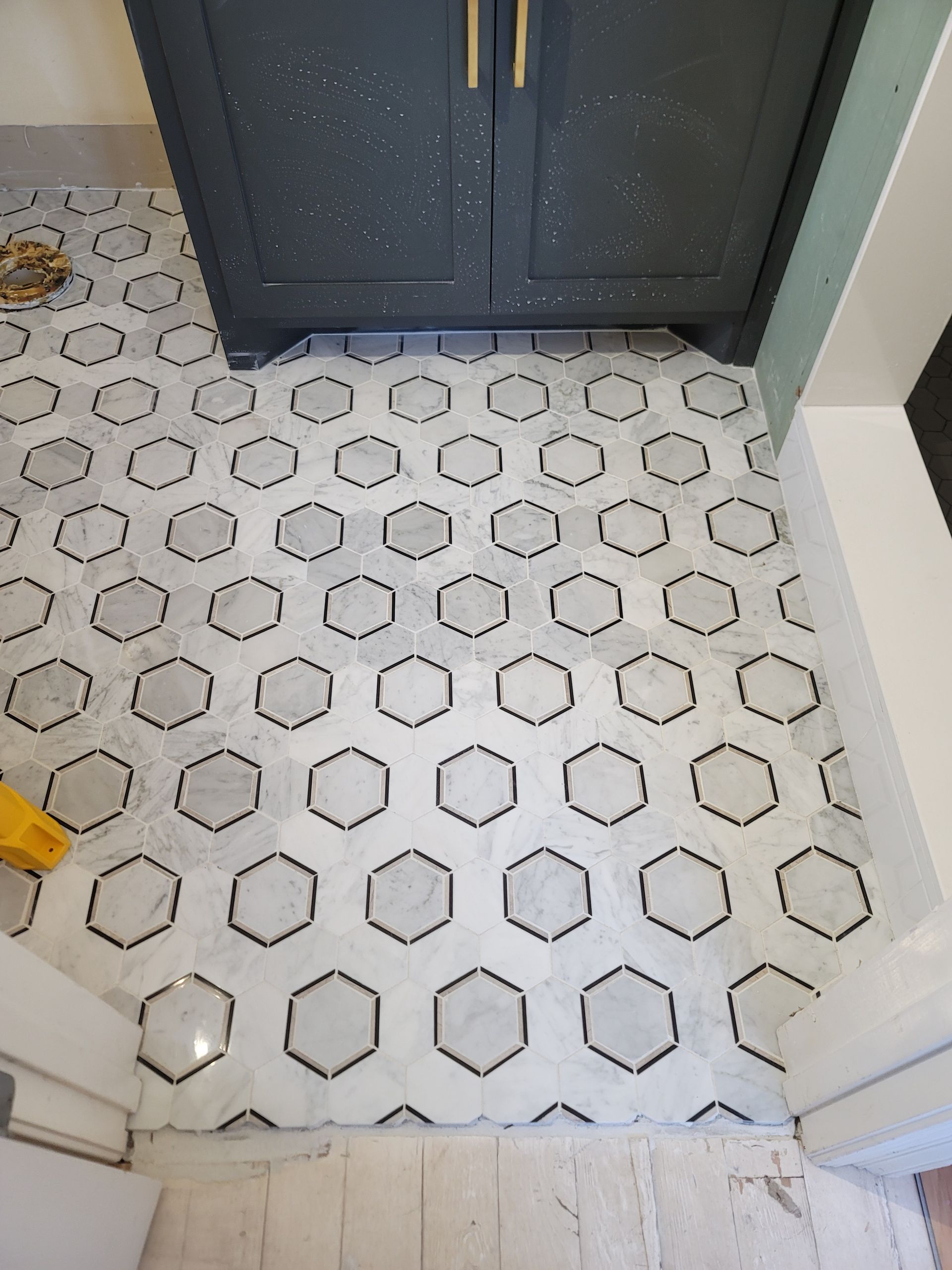 White hexagon tile floor with dark cabinets and a small yellow object at left edge