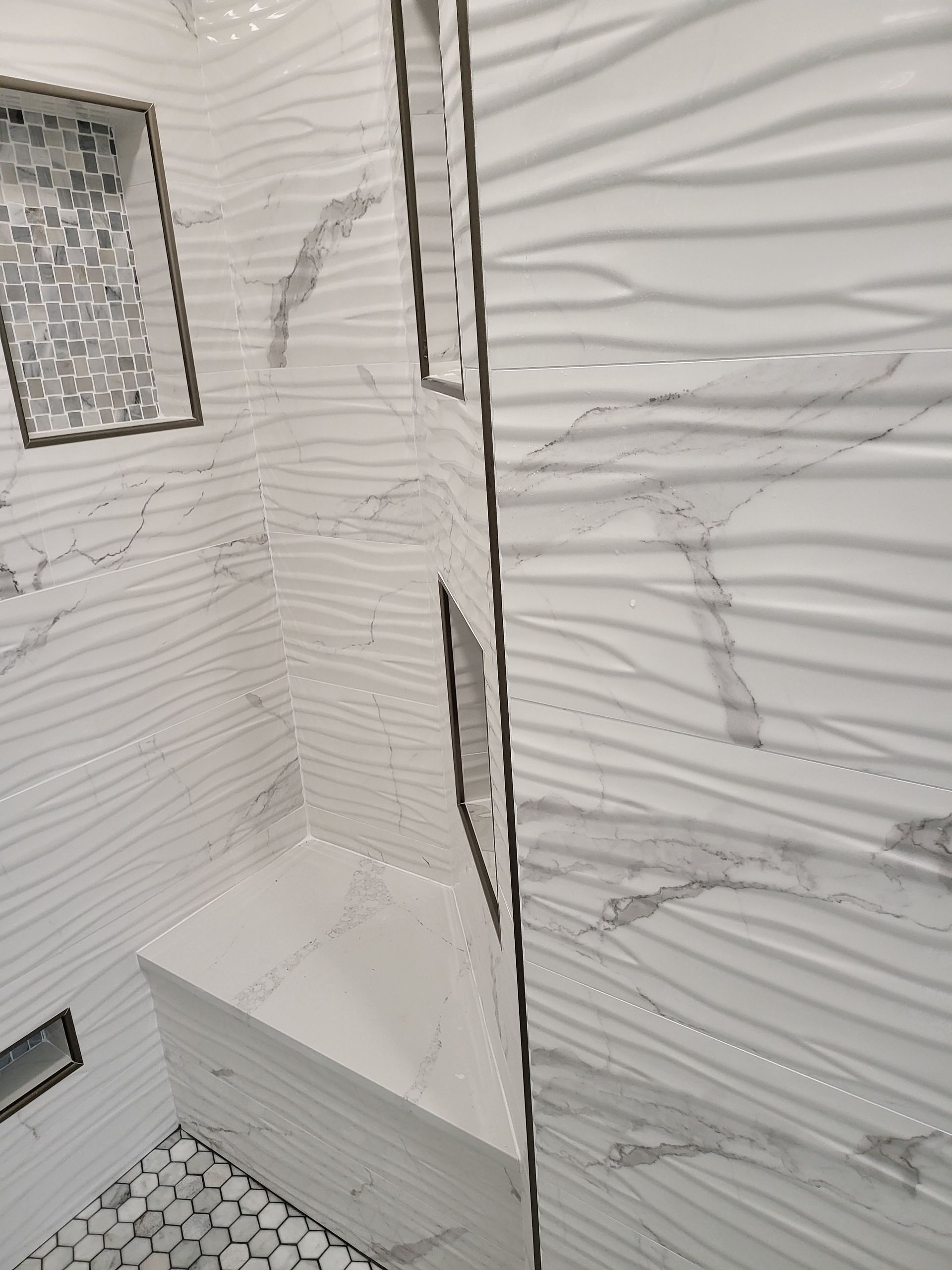 Modern white bathroom with wavy tiled walls, shower area, and mosaic tile floor