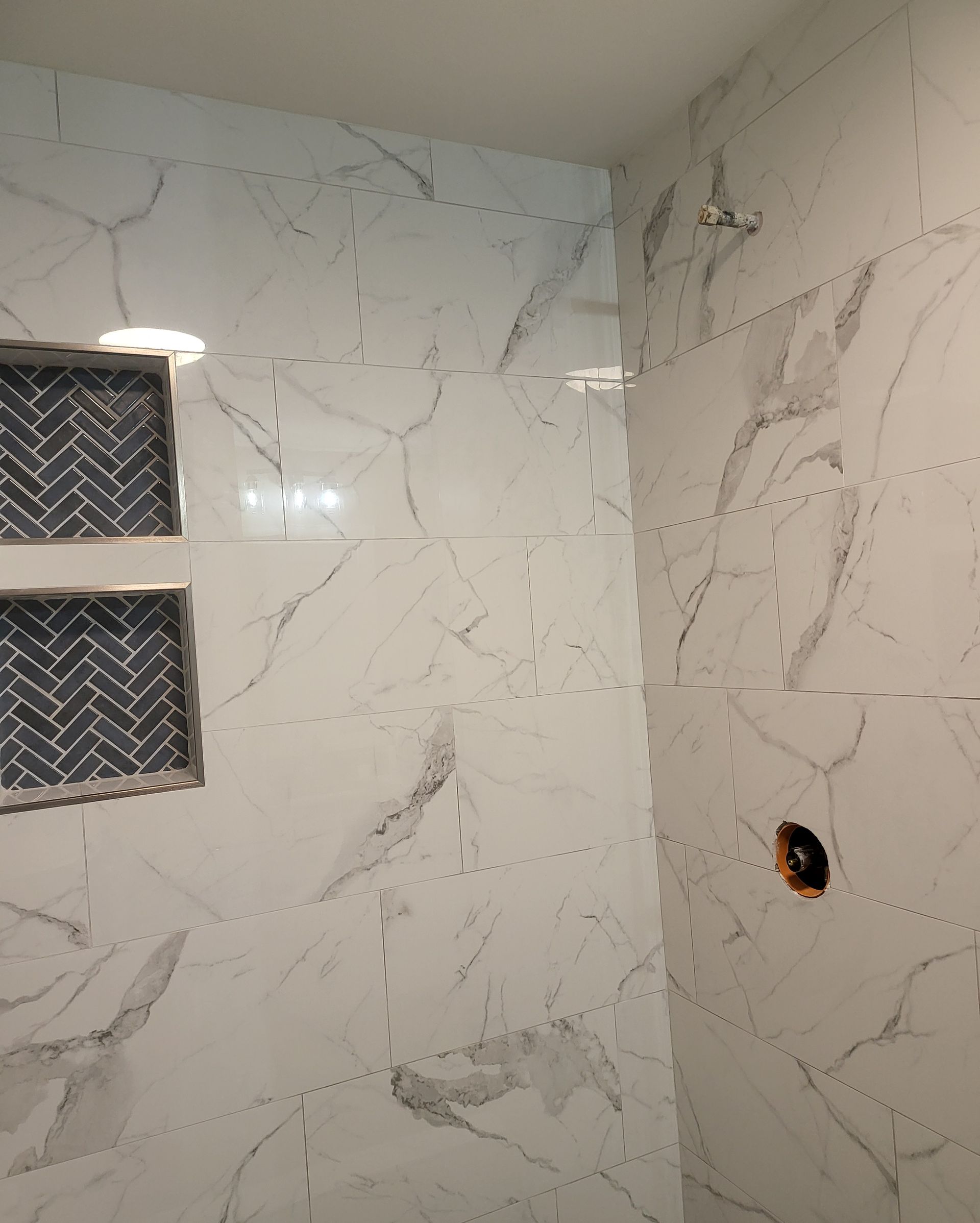 White marble-tile bathroom wall with a window and an exposed light fixture hole