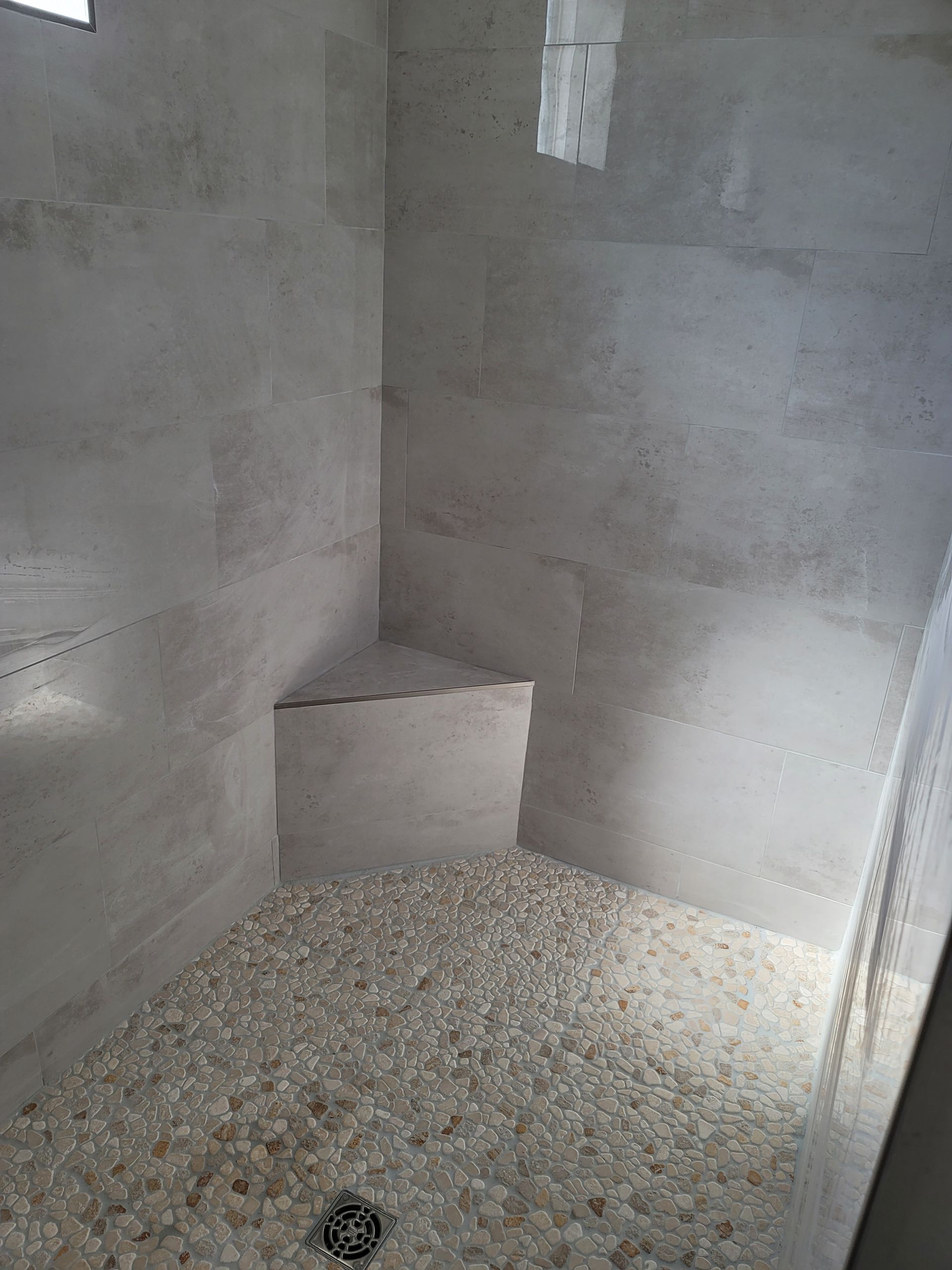 Empty gray concrete room with gravel floor and a small raised concrete step in the back corner