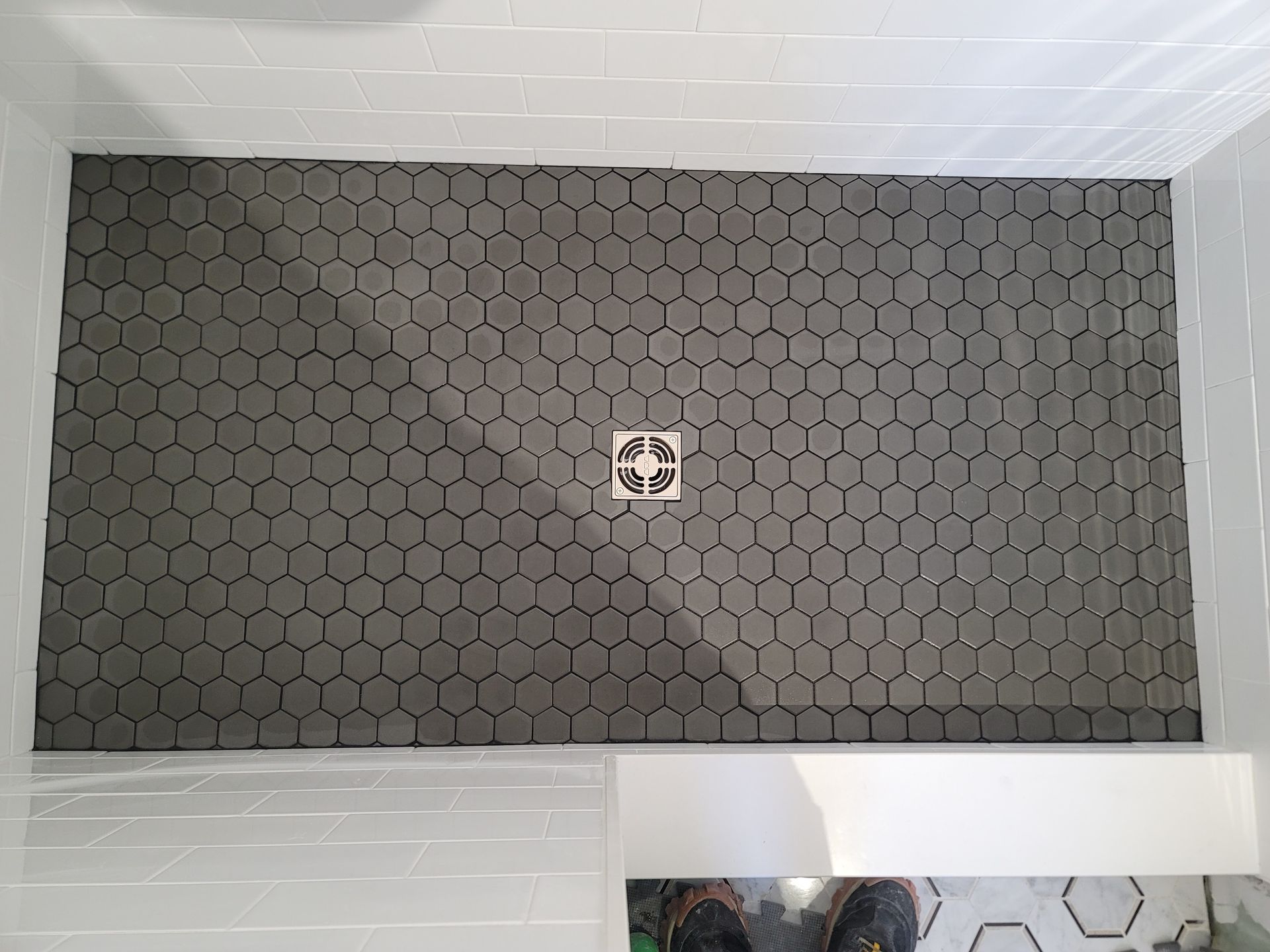 Gray hex-patterned floor mat with a small drain cover centered in a room.