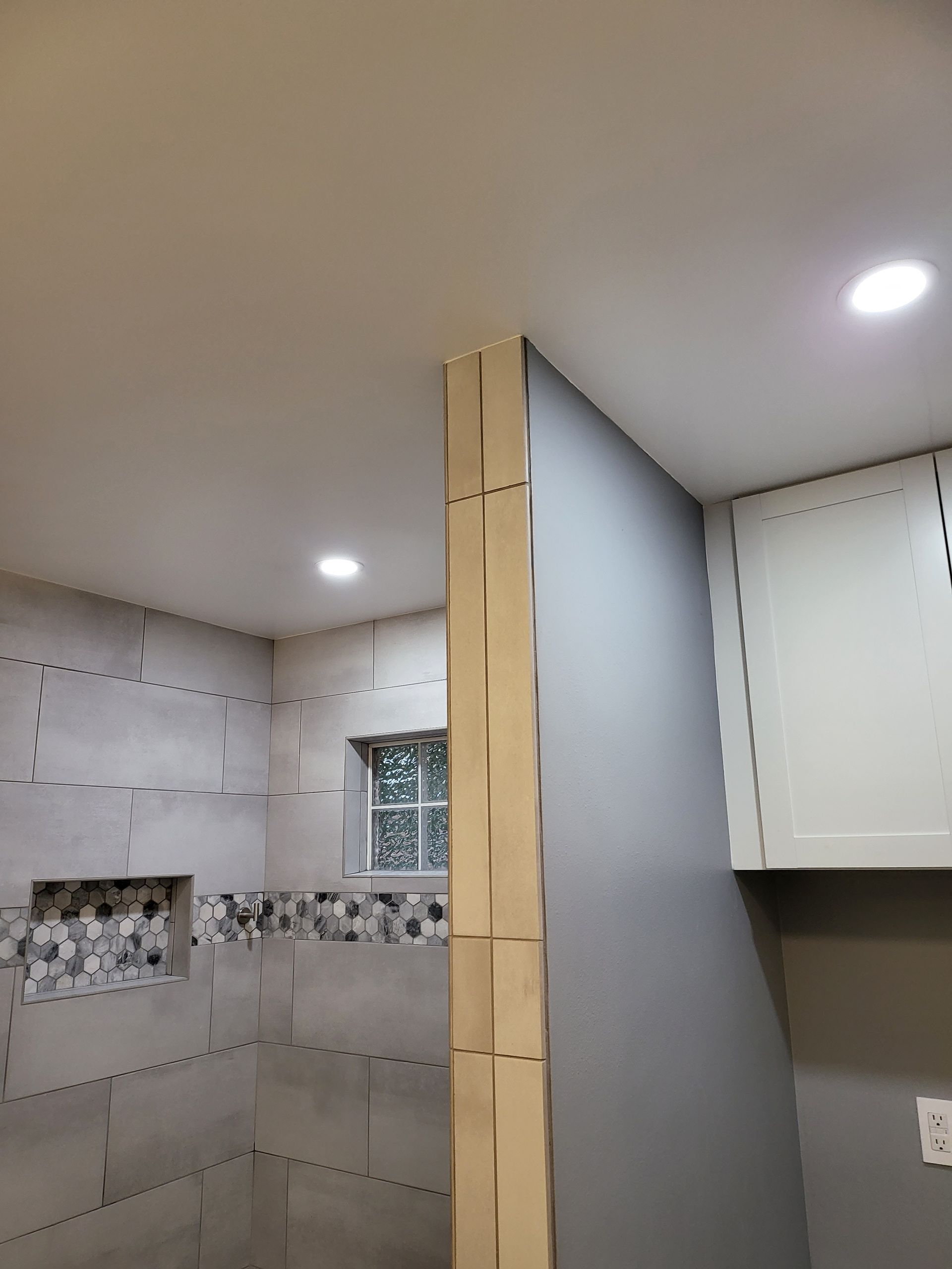 Partially tiled bathroom with a wooden support post and recessed ceiling lights