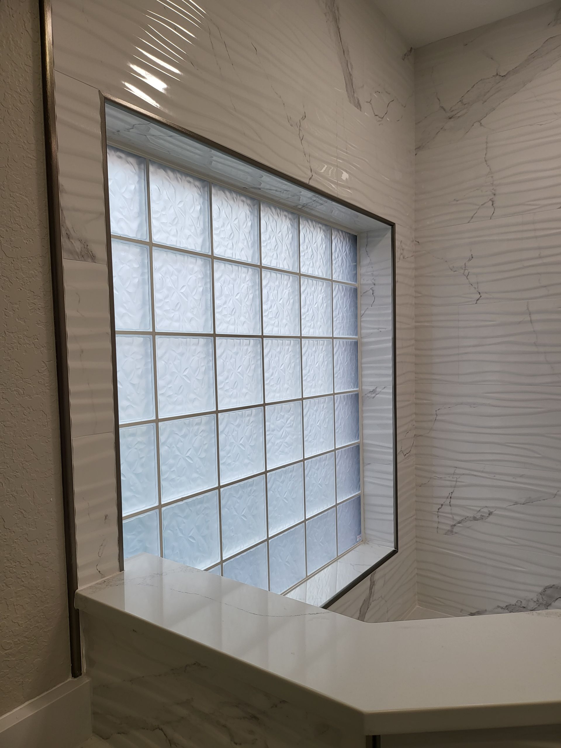 Modern interior with white walls, a frosted glass block window, and a curved white counter or ledge.