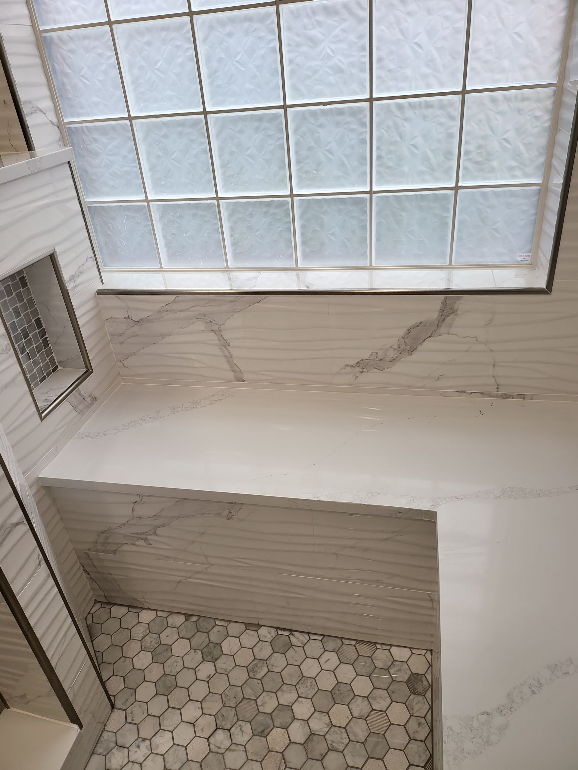 Tiled shower room with frosted glass ceiling, white walls, and a small hexagonal-tile floor area