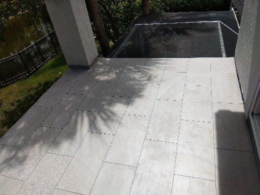 Outdoor stone patio with a sunlit walkway leading to a shaded stairwell or lower level entrance