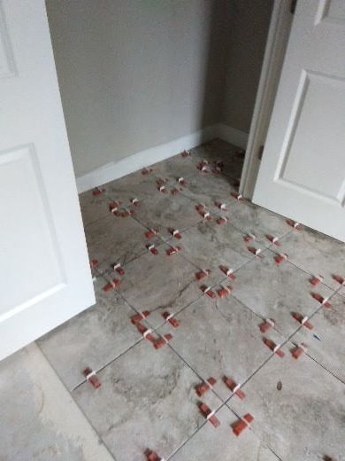Scattered red and white debris on a gray tiled floor in a doorway area