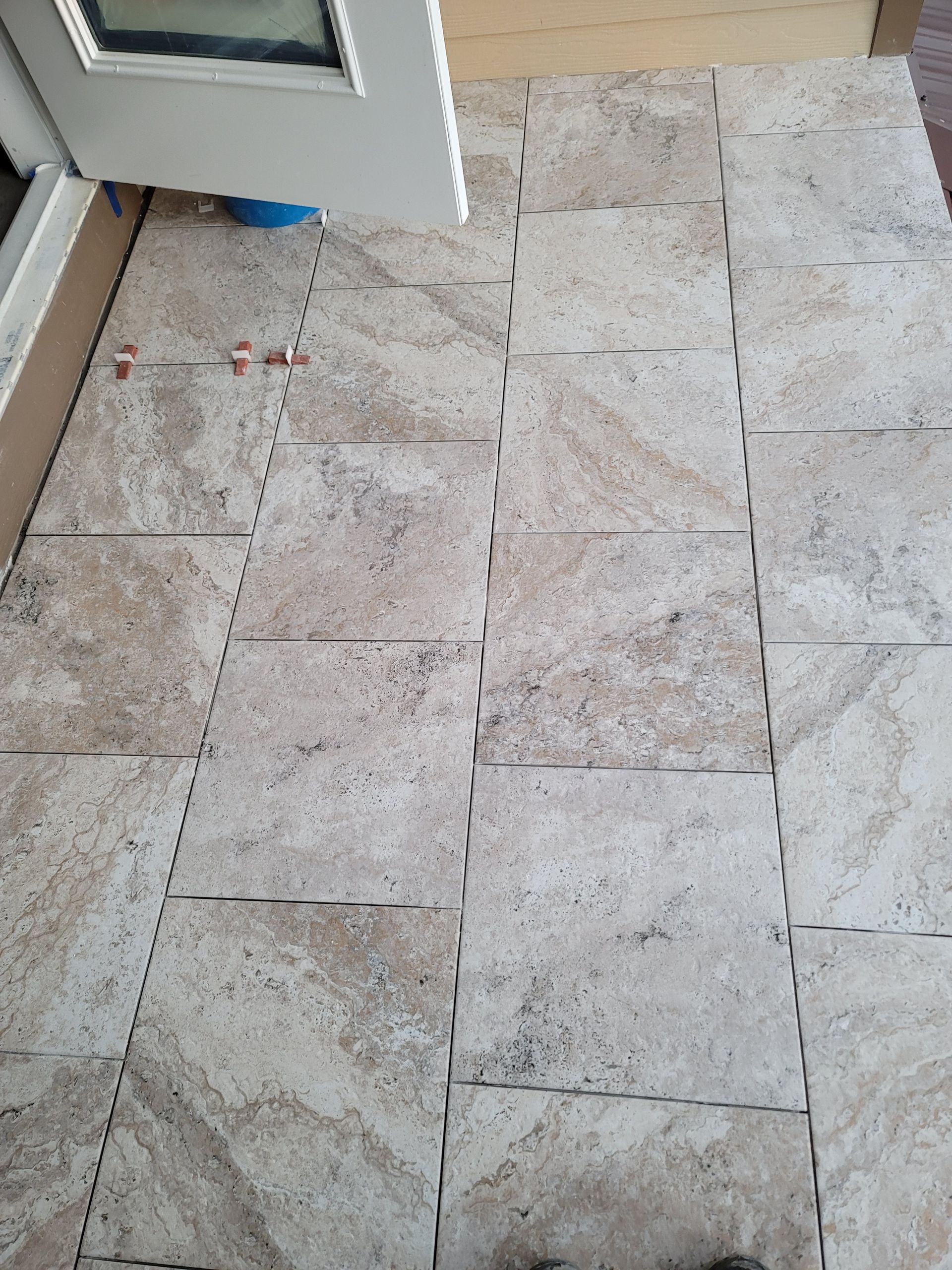 Stone-tiled outdoor floor beside a doorway, with a small red object near the wall.