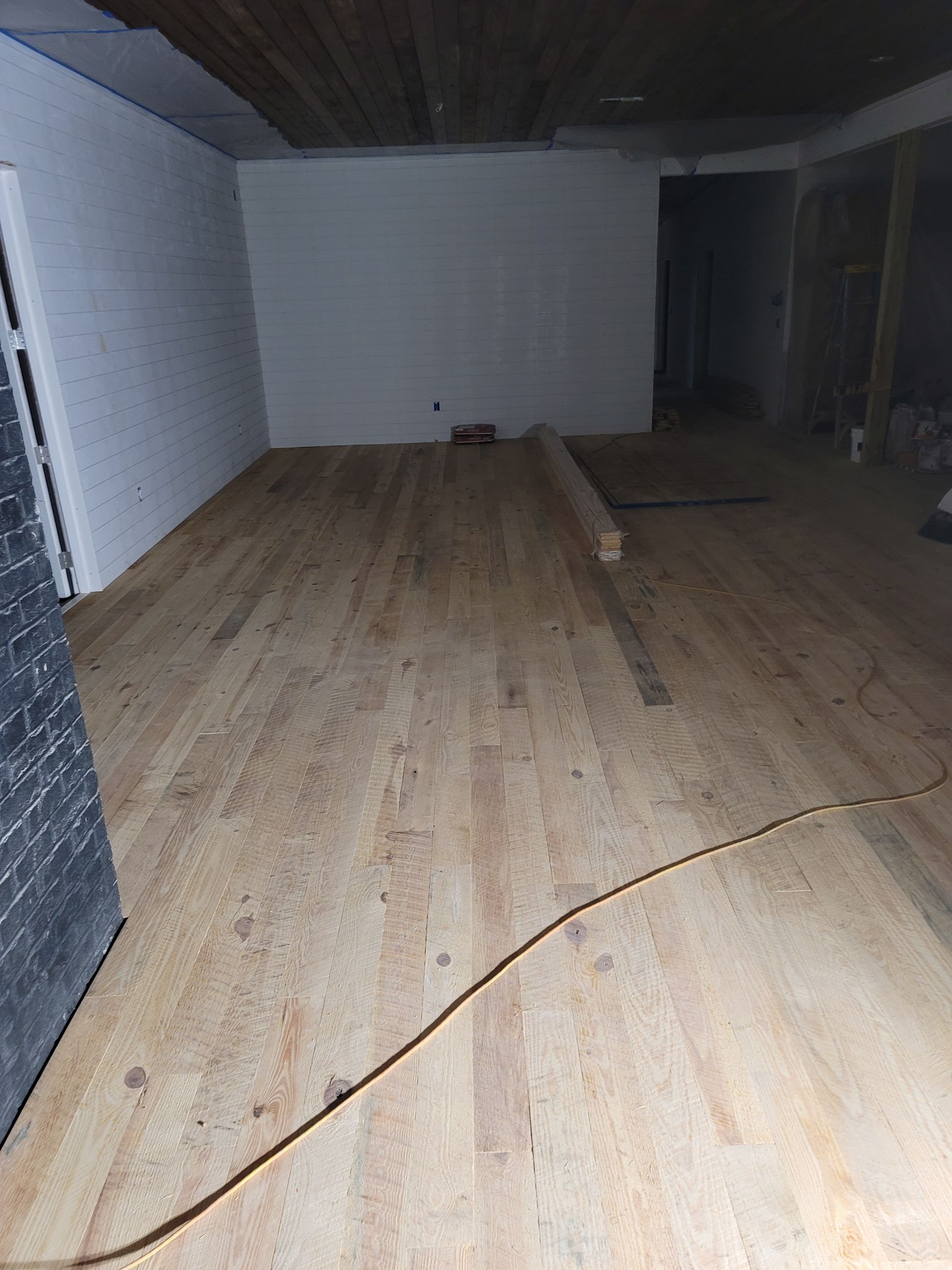 Empty room with light wood floor, white walls, and a long crack across the floorboards.