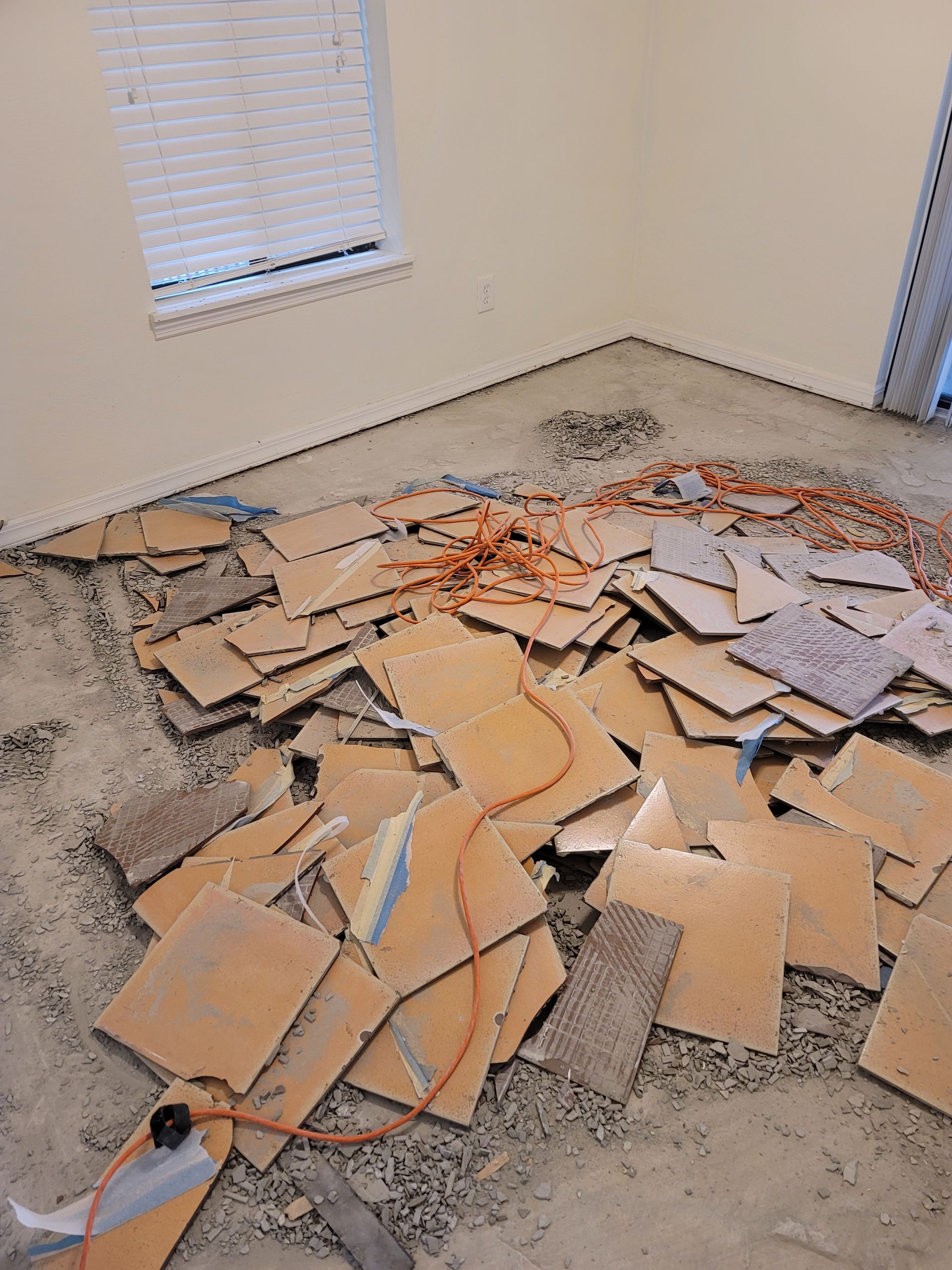 Pile of broken cardboard and debris scattered on a carpeted floor in a bare room.