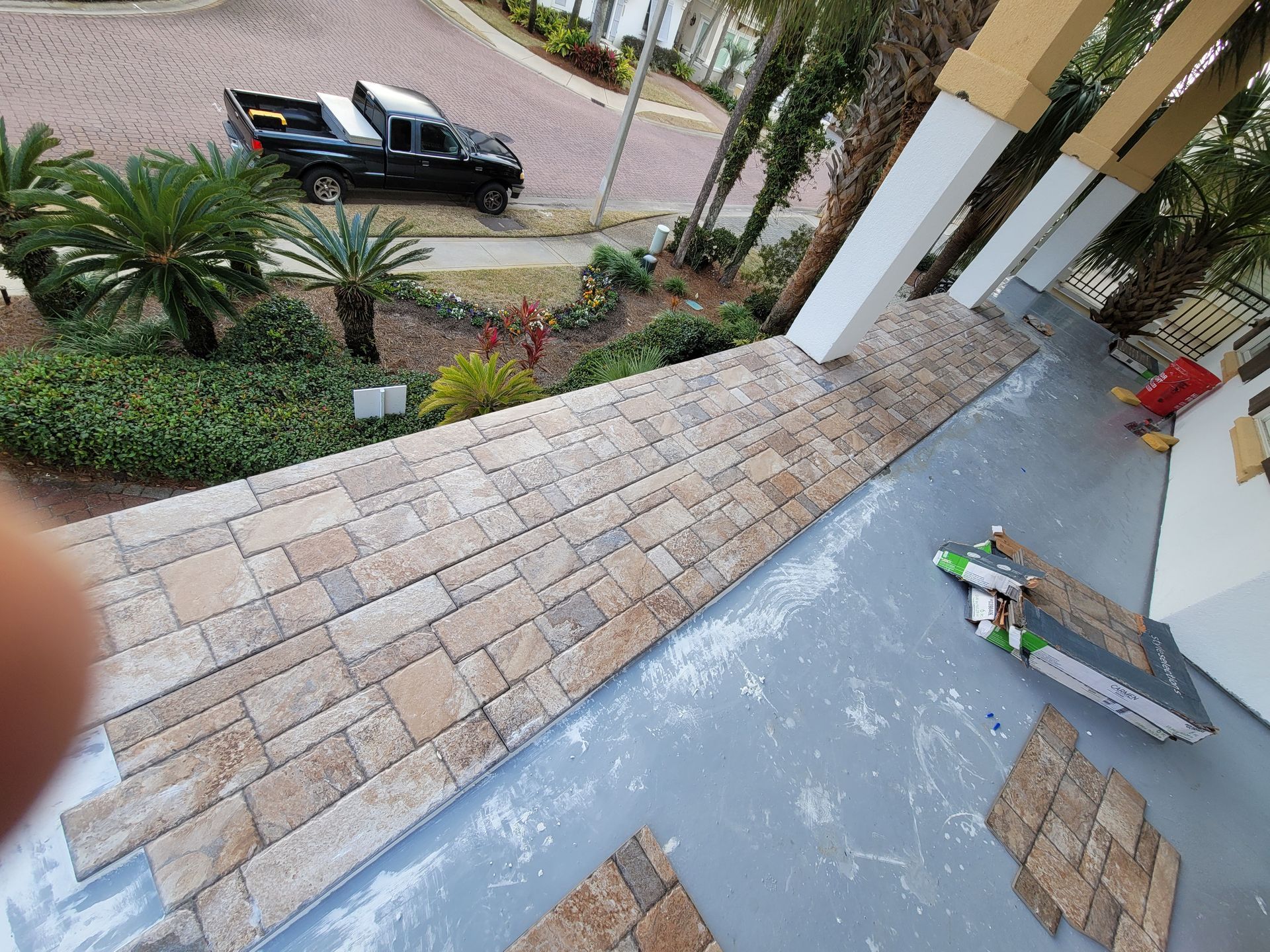 Porch under construction with stone pavers, tools, and a pickup truck parked on the driveway.